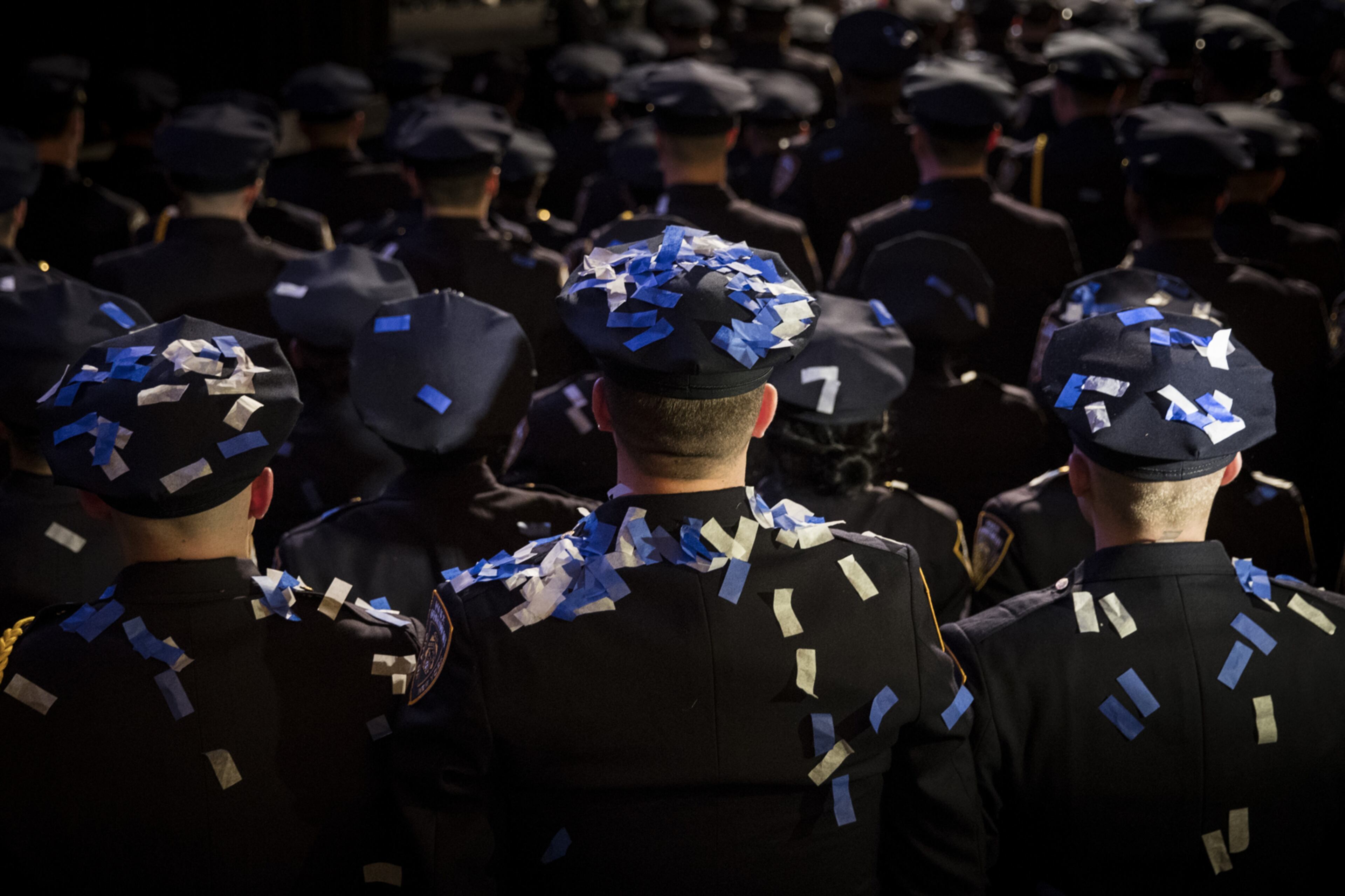 NEW YORK, NY - MARCH 30: With confetti on their hats and uniforms, the newest members of the New York City Police Department (NYPD) stand at attention at the conclusion of their police academy graduation ceremony at the Theater at Madison Square Garden, March 30, 2017 in New York City. Over 600 new officers were sworn in during the ceremony. (Photo by Drew Angerer/Getty Images)