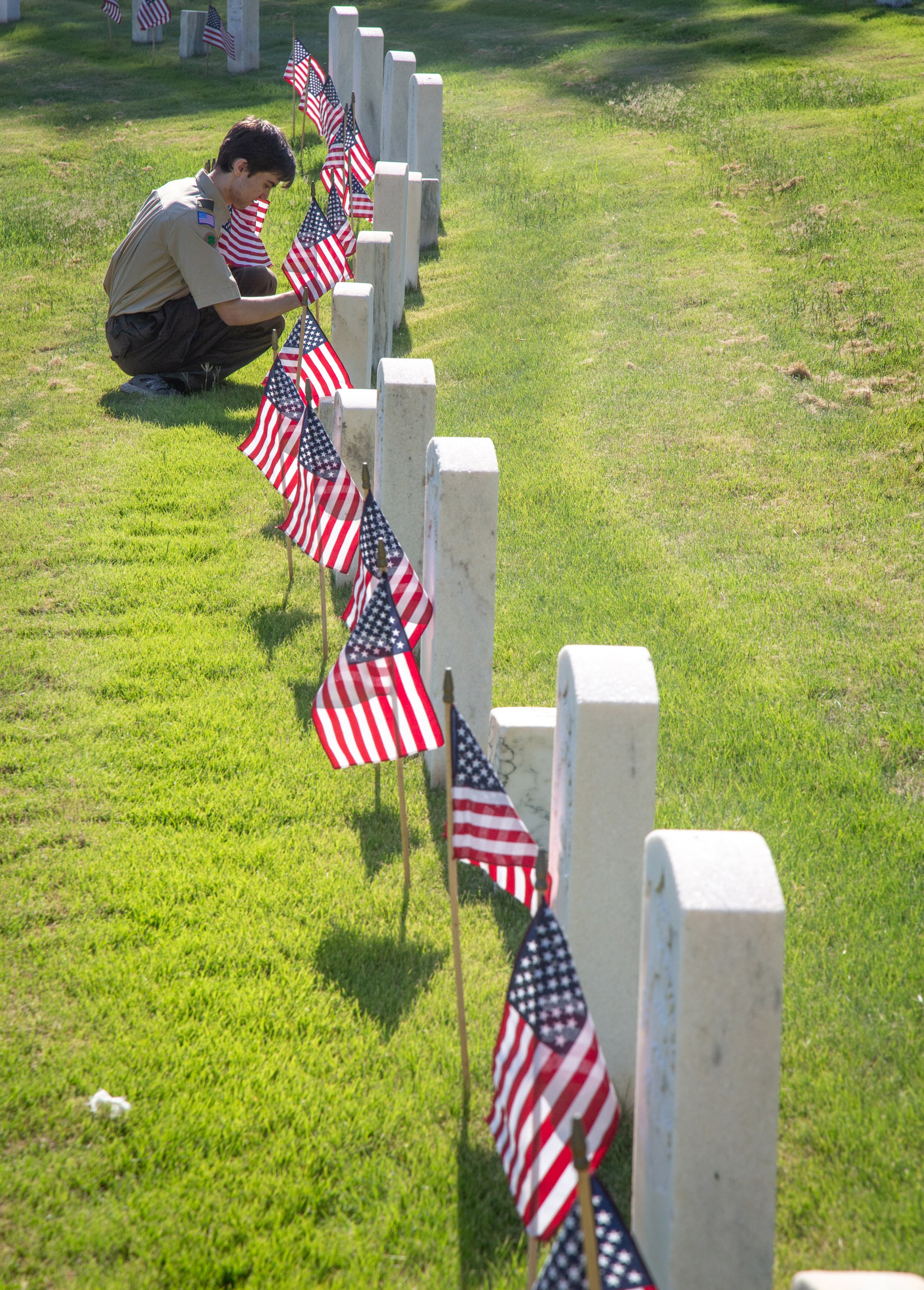 Matthew King from Troop 1099 places an Americain flag at one of the many grave sites at the Marietta National Cemetery on Saturday, May 25, 2019. Scouts placed an American flag at each of the 18,000 graves in advance of the Memorial Day commemorations. STEVE SCHAEFER / SPECIAL TO THE AJC