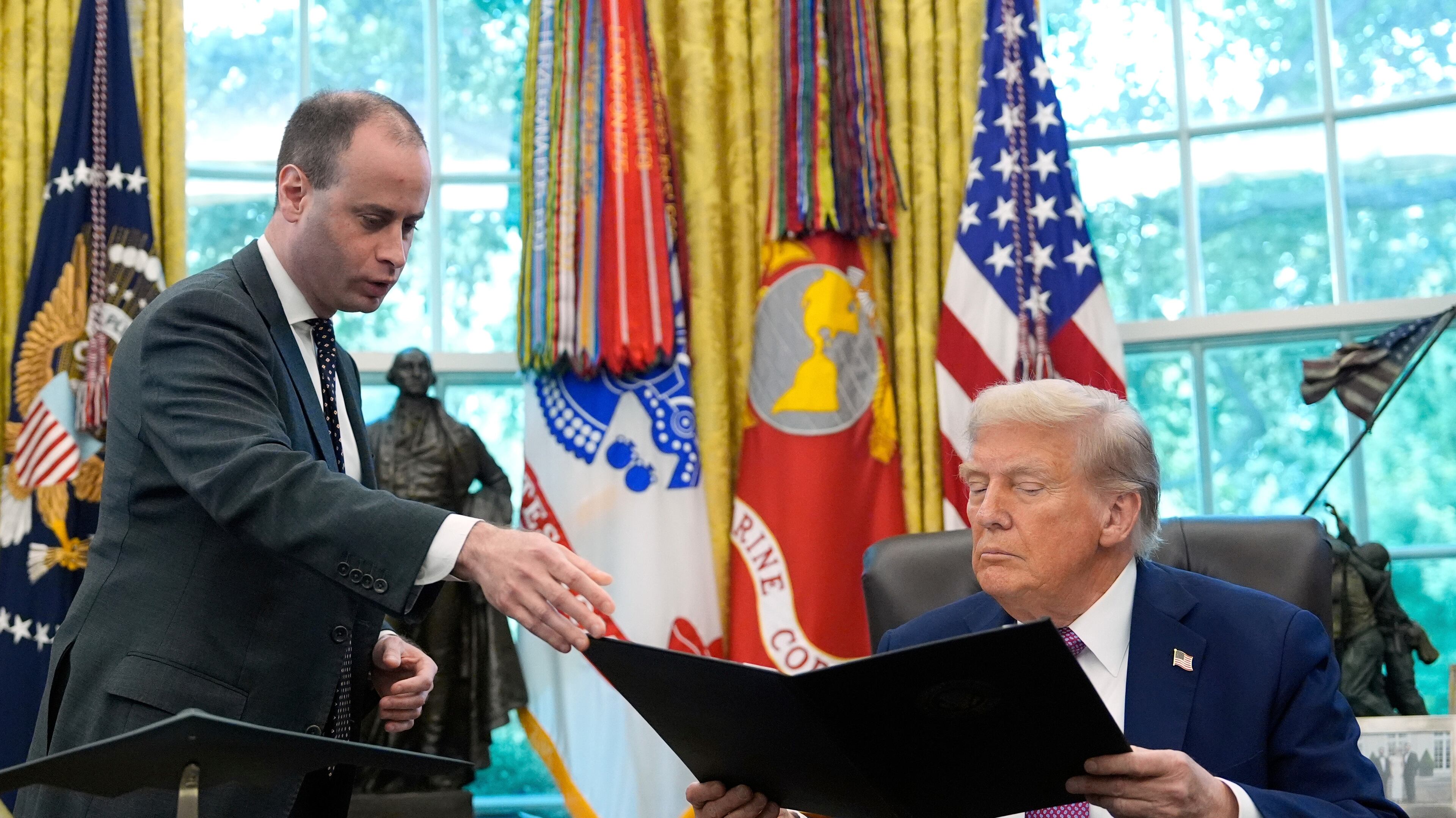 FILE - White House staff secretary Will Scharf, left, hands President Donald Trump an executive order to sign in the Oval Office of the White House, Sept. 5, 2025, in Washington. (AP Photo/Alex Brandon, File)