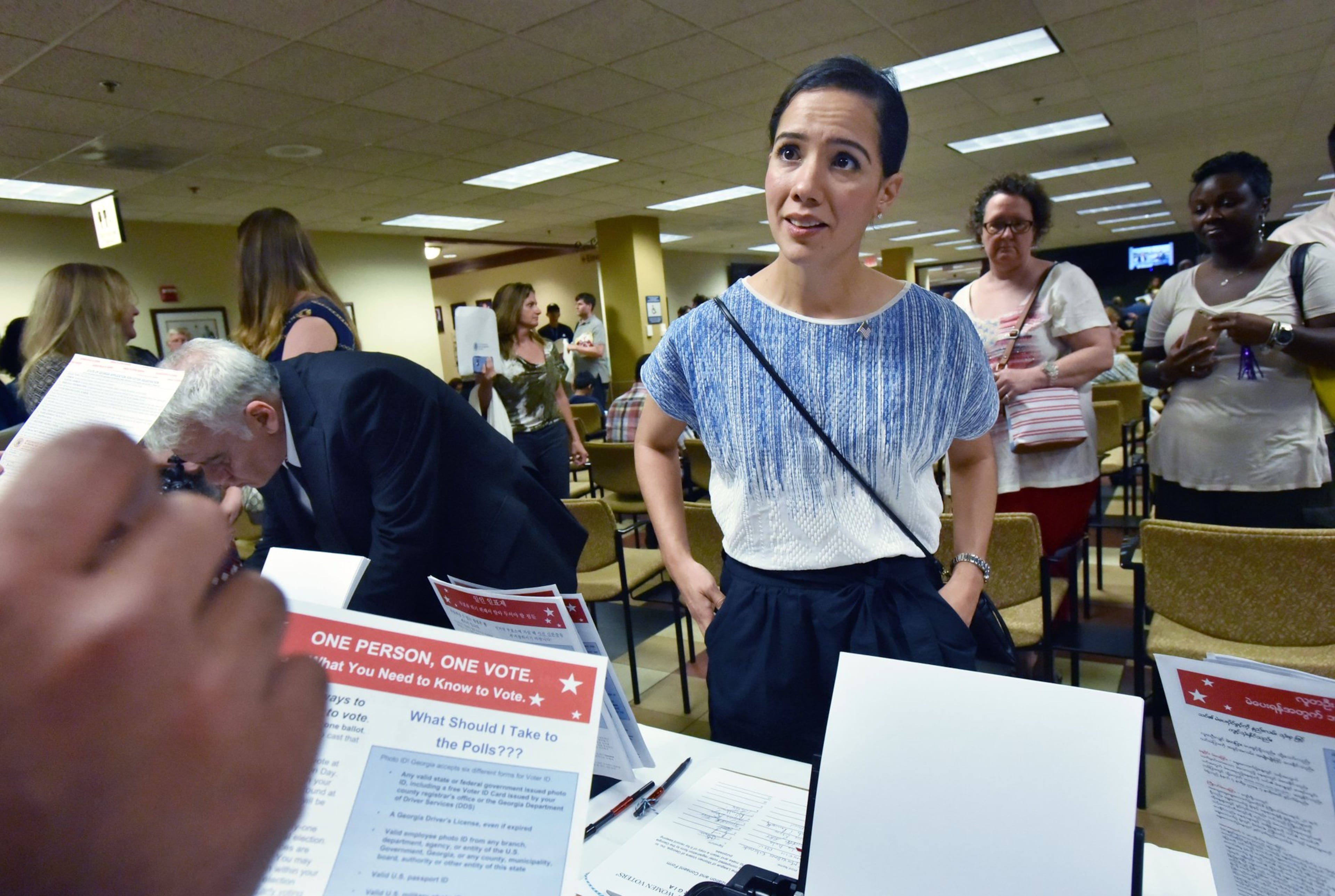 Newly naturalized citizen Perla Freed, originally from Honduras, completes her voter registration, helped by Samuel Aguilar (left, hand showing), with Georgia Association of Latino Elected Officials, after her naturalization ceremony at the USCIS Atlanta Field Office. (Hyosub Shin/AJC 2016)
