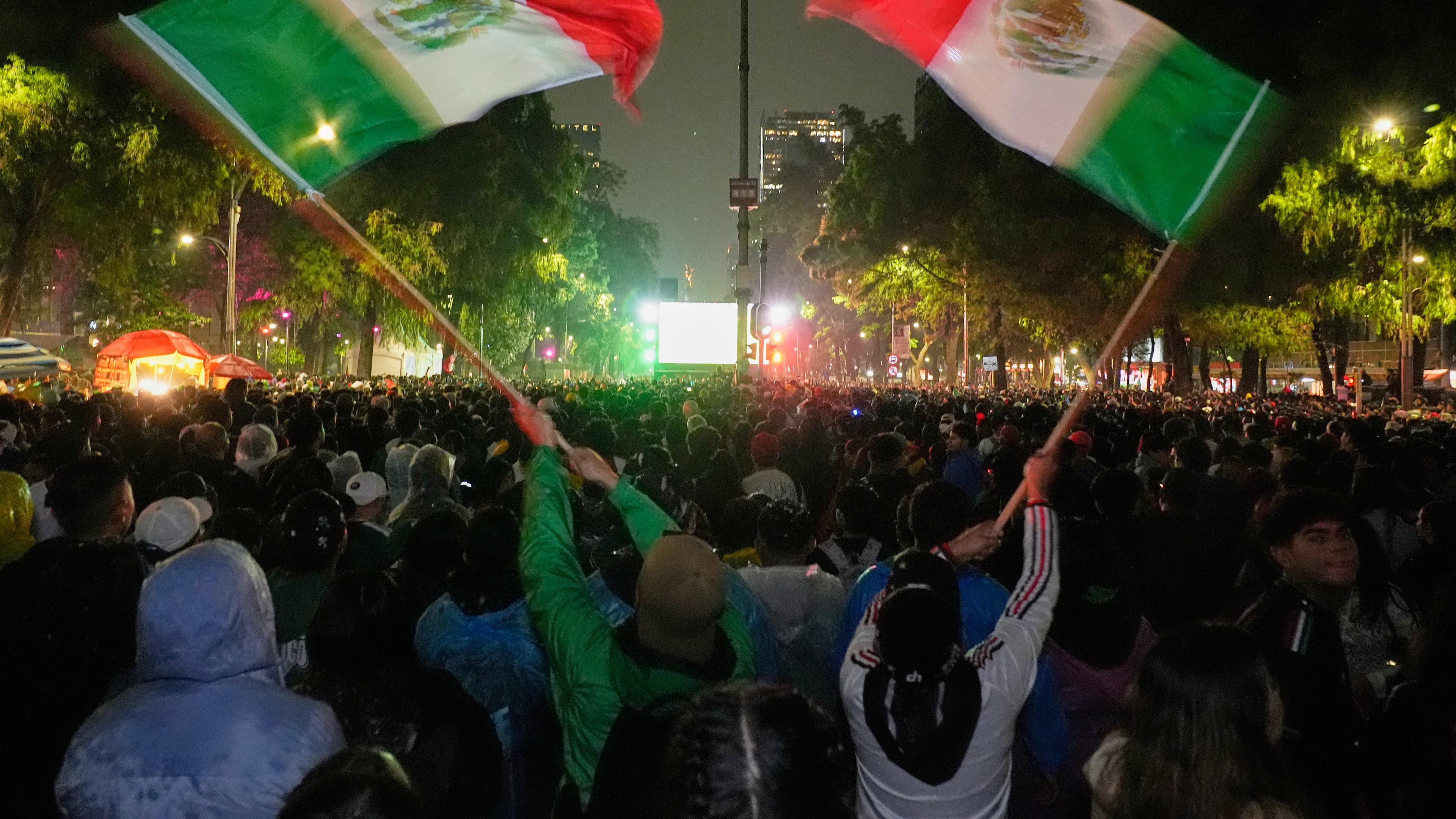 Mexican fans wave flags as they watch the World Cup round of 32 soccer match between Mexico and Ecuador near the Angel of Independence monument in Mexico City, Tuesday, June 30, 2026. (AP Photo/Marco Ugarte)