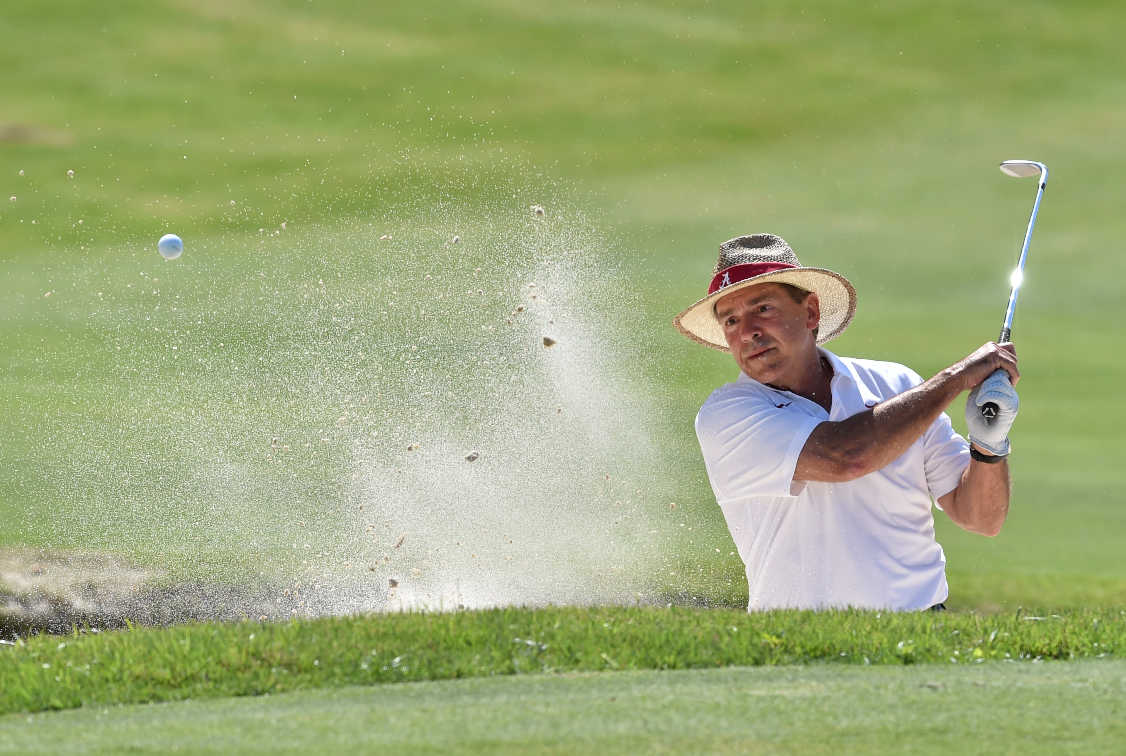 Alabama head football coach Nick Saban hits from the bunker on the 18th hole during the Chick-fil-A Peach Bowl Challenge at Reynolds Plantation Tuesday April 28, 2015. Saban and his playing partner Mark Ingram lost to Georgia Tech head football coach Paul Johnson and his partner Jon Berry after four playoff holes. The event features NCAA head coaches and former athletes and celebrities from the same school competing against their rivals for a share of a $520,000 scholarship purse. BRANT SANDERLIN/BSANDERLIN@AJC.COM