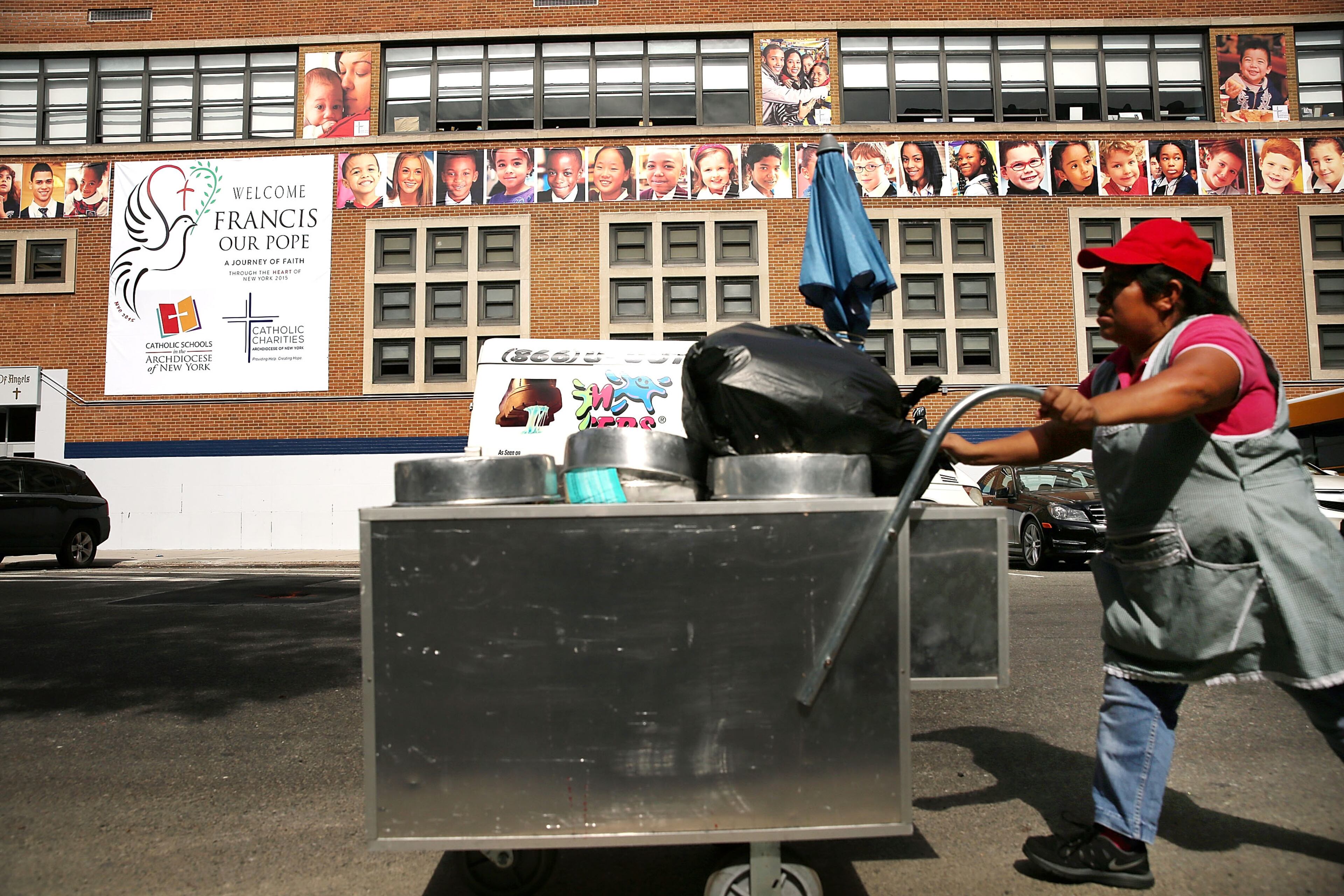 A woman selling ices walks by Our Lady Queen of Angels School in East Harlem where Pope Francis is scheduled to visit in New York City. The Pope will be making his first trip to the United States on a three-city, five-day tour that will begin in Washington on September 22, then travel to New York City and Philadelphia. The Pope will depart on September 27. (Photo by Spencer Platt/Getty Images)