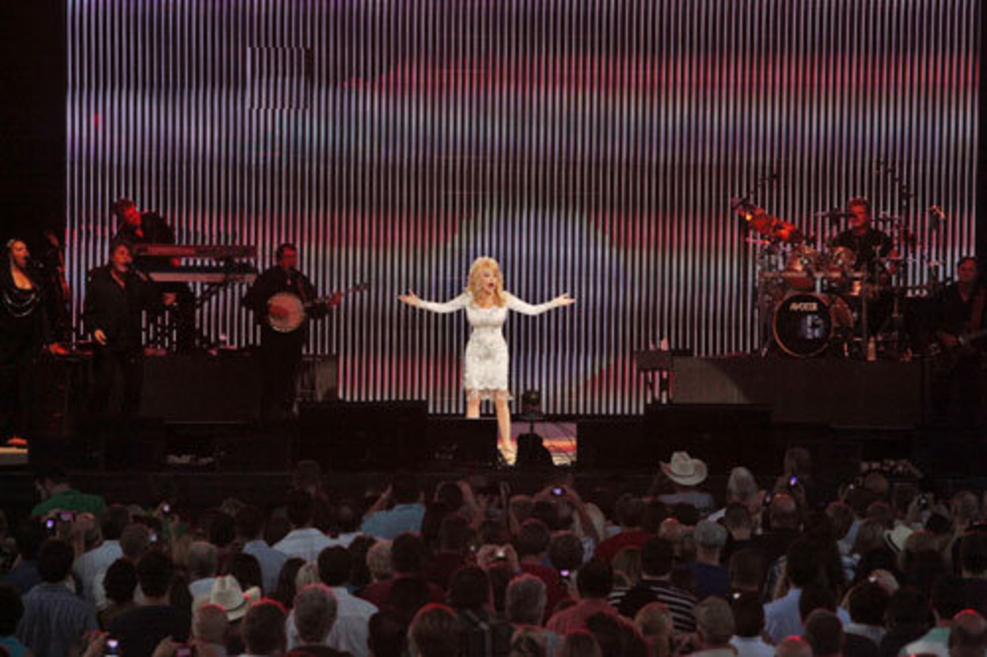 Audience members snap photos of 65-year-old Dolly Parton as she performs.