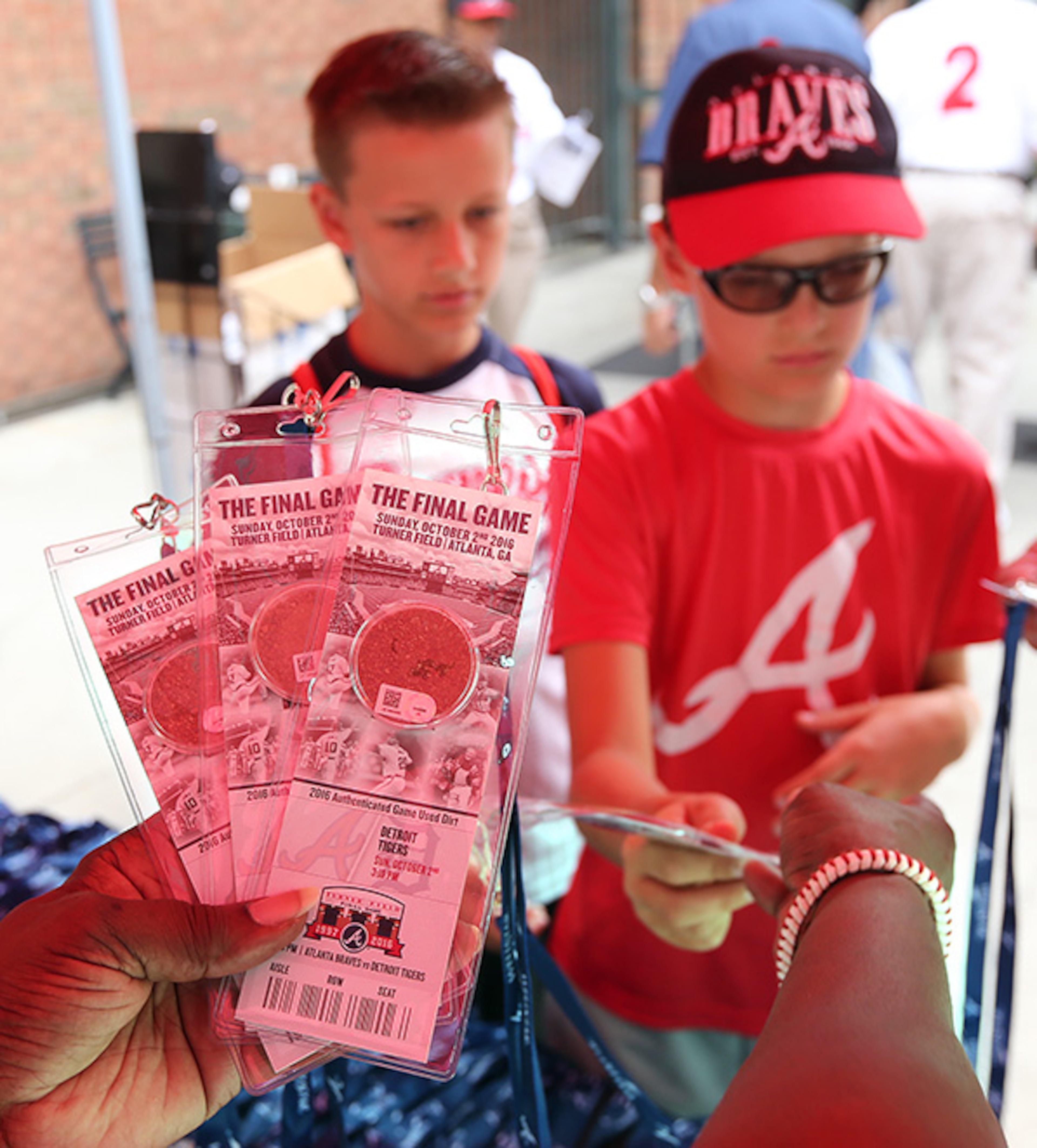 October 02, 2016 Atlanta: Debra Green hands out 2016 authenticated game used dirt from Turner Field to fans including Rylan (left) and Jaxen Christen, Peachtree City, arriving for the final Braves game at Turner Field on Sunday, Oct. 2, 2016, in Atlanta. The team will move to a new stadium in Cobb County for the 2017 season. Curtis Compton /ccompton@ajc.com