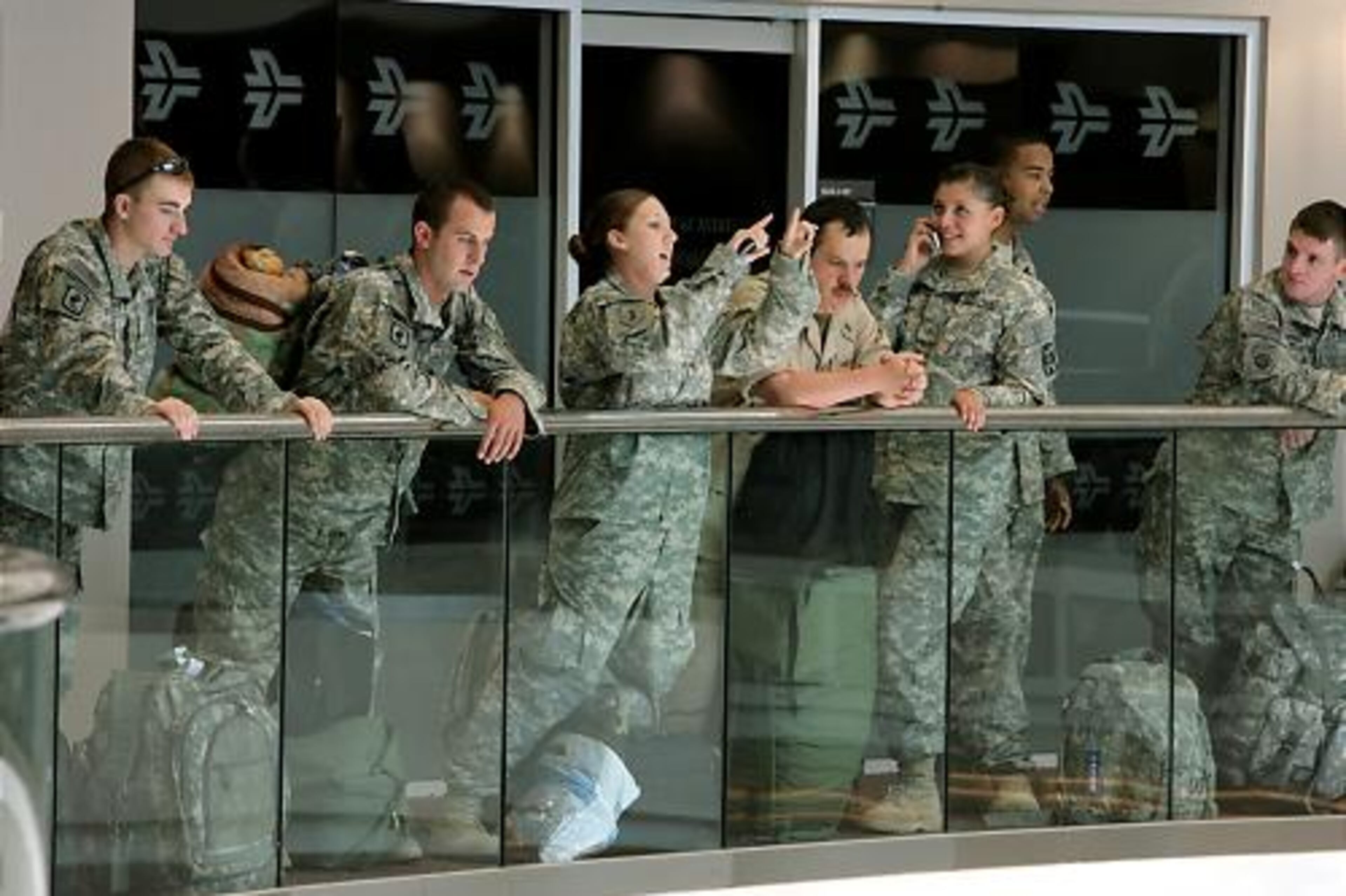 Soldiers, returning to Iraq, wait outside the USO above the airport's atrium.