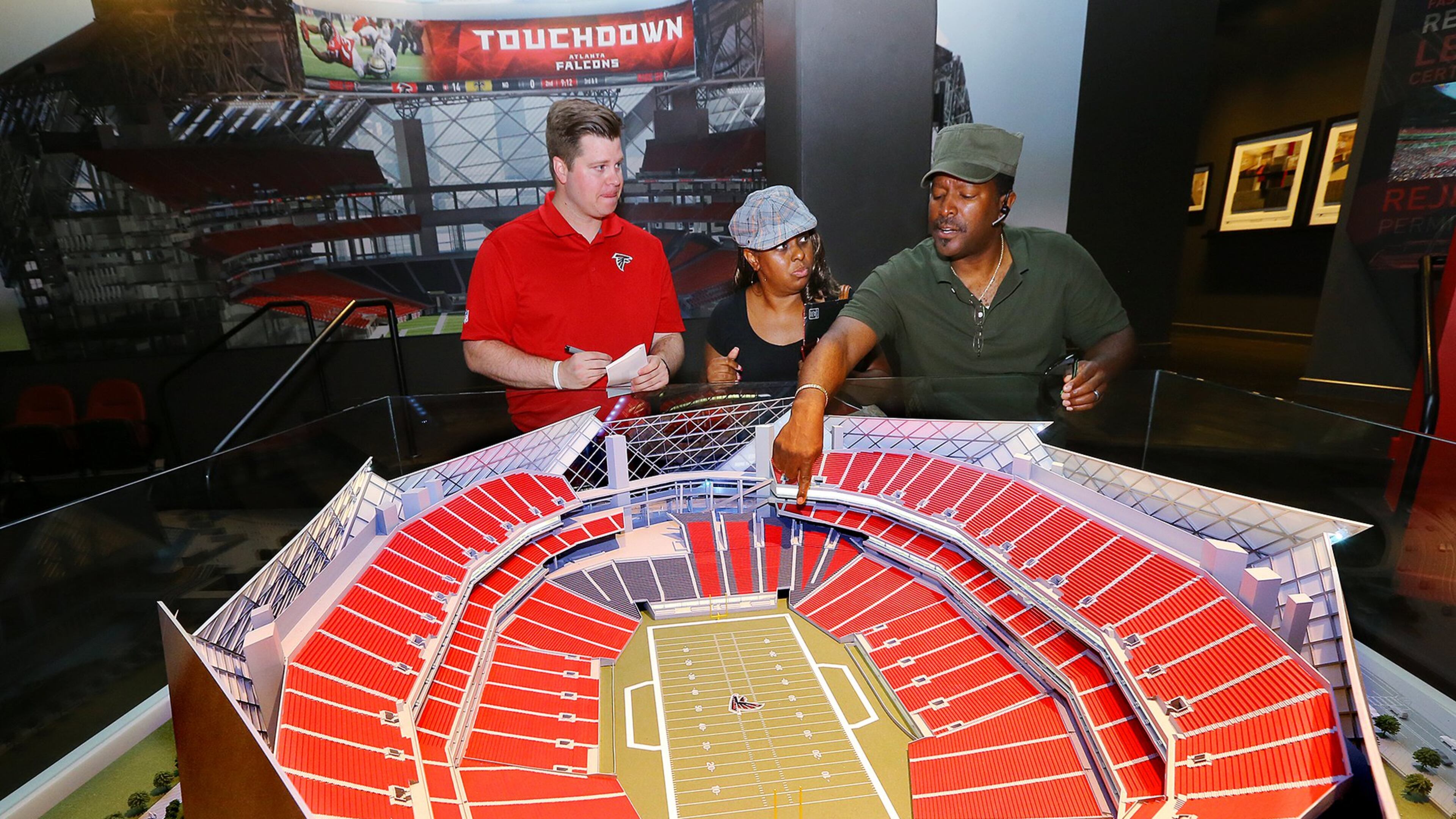 College Football Playoff officials will visit the Falcons’ stadium preview center today. The center includes a replica of the new downtown stadium. Falcons fans Valerie and Reginald Fitzpatrick are shown considering the location of their season tickets last month in a meeting with sales consultant Matt Salata. Photo by Curtis Compton/ccompton@ajc.com