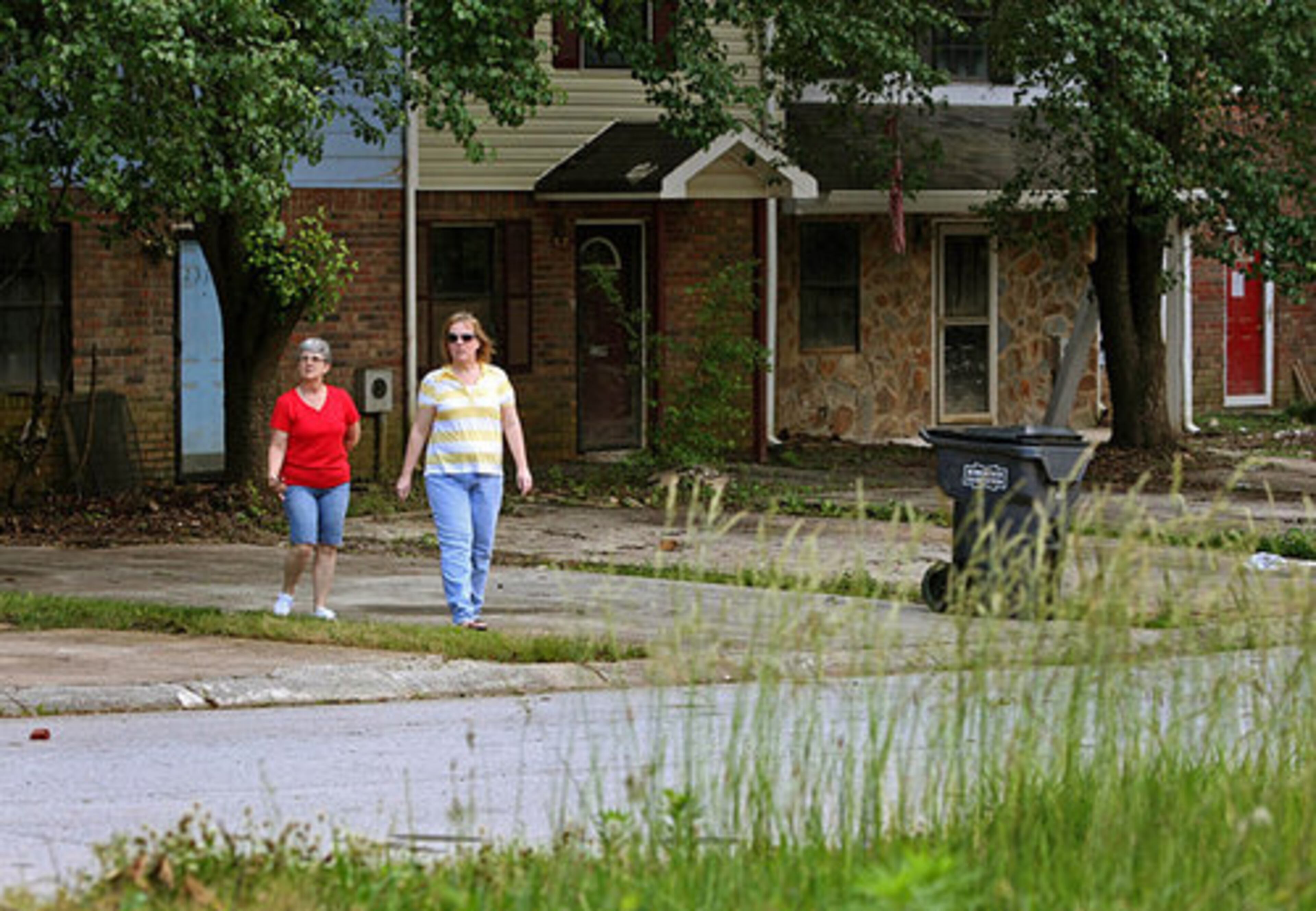 Rita Rivard-Carson, left, walks with neighbor Keely Ziegler as they walk at the end of their neighborhood, which was destroyed by the September 2009 floods Monday afternoon in Austell, Ga., May 24, 2010. Since the flood destroying most of the homes in her neighborhood, she's been drowning in mortgage payments. She's been advised to just walk away, but the obstacles she had to overcome to buy the home in 2005 makes walking away seem impossible.