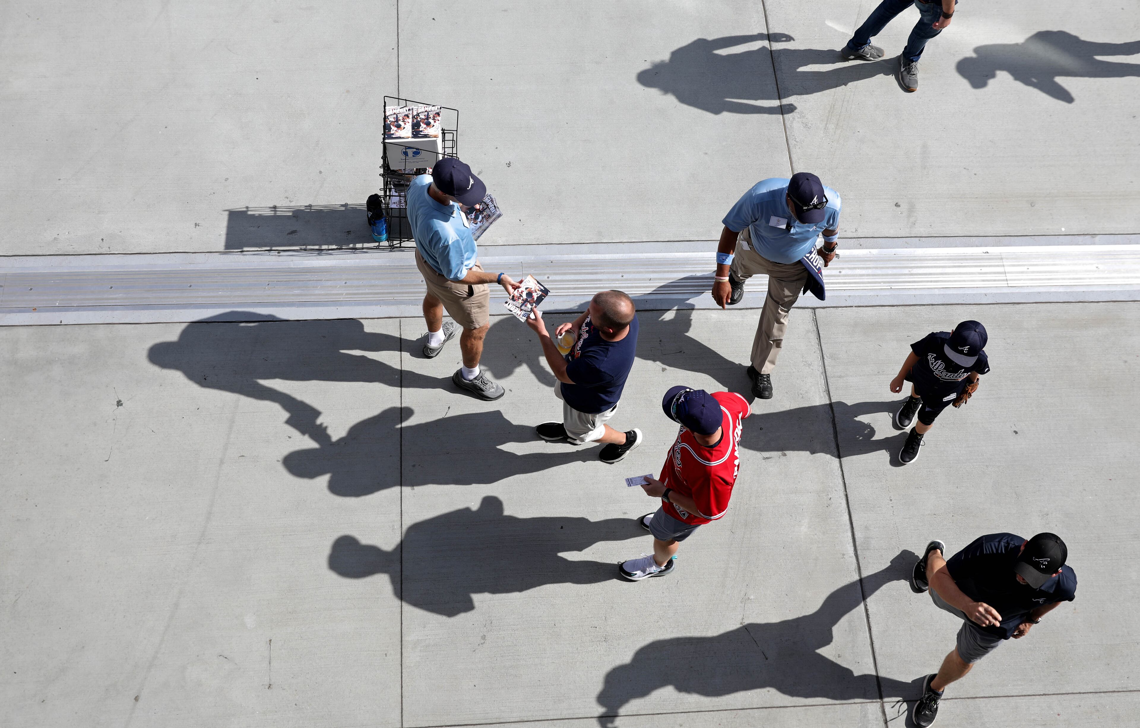 An usher passes out programs to fans as they enter the Club House gate before Game 4 of the Braves-Dodgers series Monday at SunTrust Park. (Jason Getz/Special)