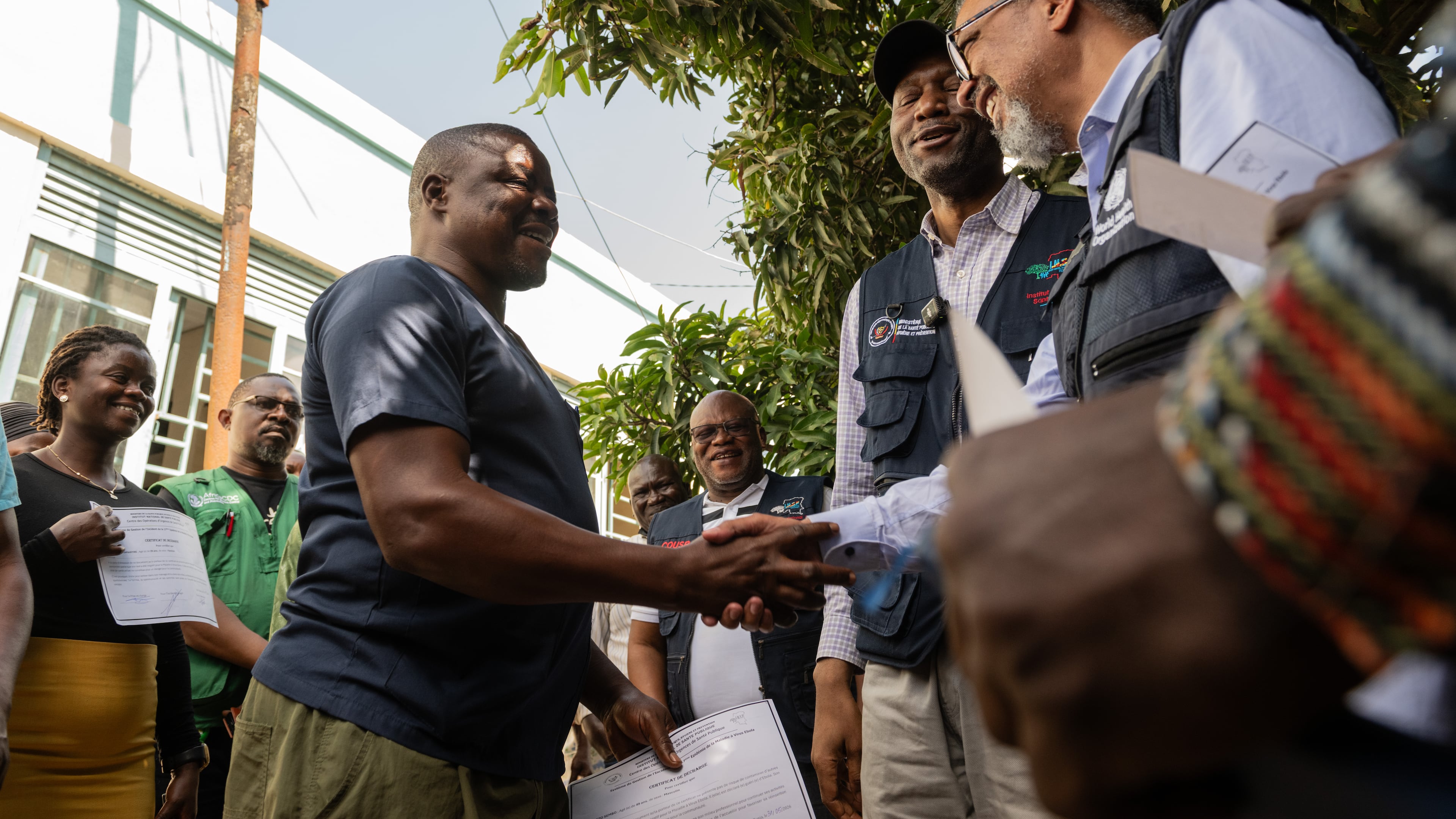 Director General of the World Health Organisation (WHO), Tedros Adhanom Ghebreyesus, right, shakes hands with Ezo Etienne, a health worker who recovered from Ebola in Bunia, Congo, Sunday, May 31, 2026. (AP Photo/Moses Sawasawa)