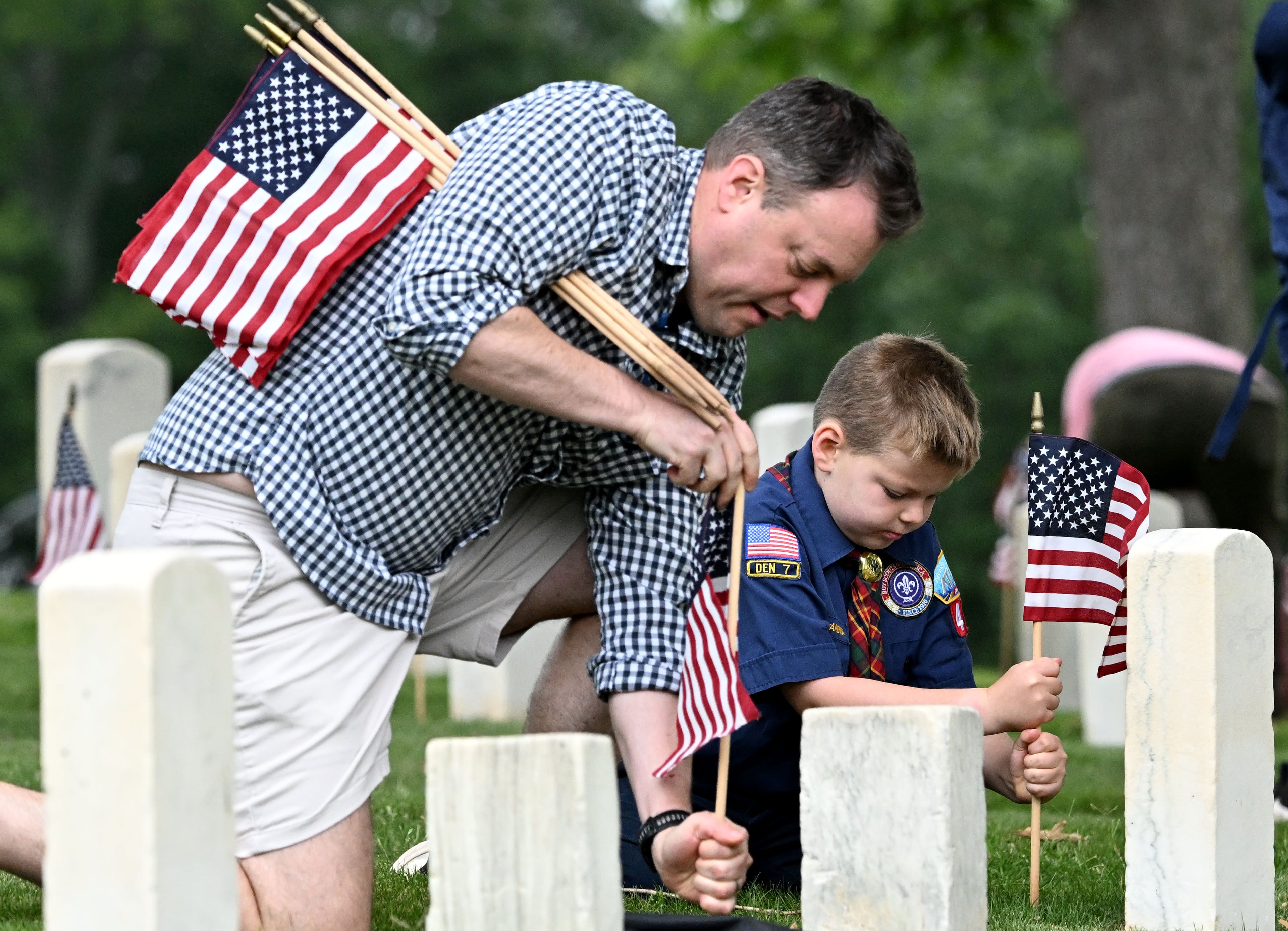 Harrison Lamontagne, 9, and his father, Michael Lamontagne, place a flag in front of a headstone during the Memorial Day Flag Placement event at Marietta National Cemetery on Saturday, May 23, 2026, in Marietta. Scouting groups in the community place more than 18,000 U.S. veteran grave flags at Marietta National Cemetery each year on the Saturday before Memorial Day, helping prepare for Monday’s ceremony. The long-running service project—organized with the National Memorial Day Association of Georgia—also gives youth and adults an opportunity to honor fallen service members and learn about their sacrifices and the area’s history. (Hyosub Shin/AJC)