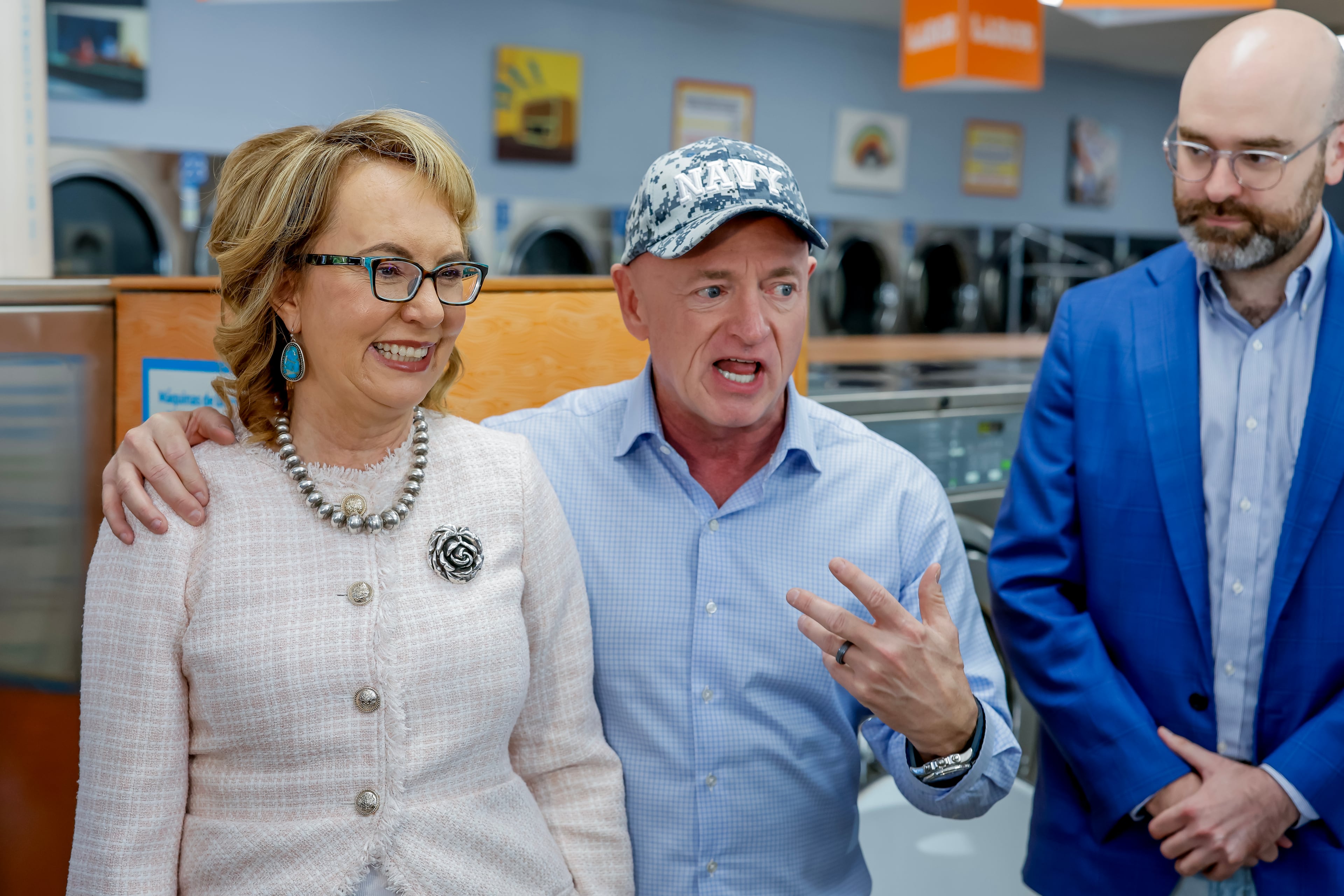 Former Arizona U.S. Rep. Gabby Giffords (left) and her husband, U.S. Sen. Mark Kelly (center), meet with Democratic lieutenant governor nominee Josh McLaurin and others during a campaign stop at the Laundry Lounge in Sandy Springs on Wednesday, Aug. 19, 2026. (Erik S. Lesser for the AJC)