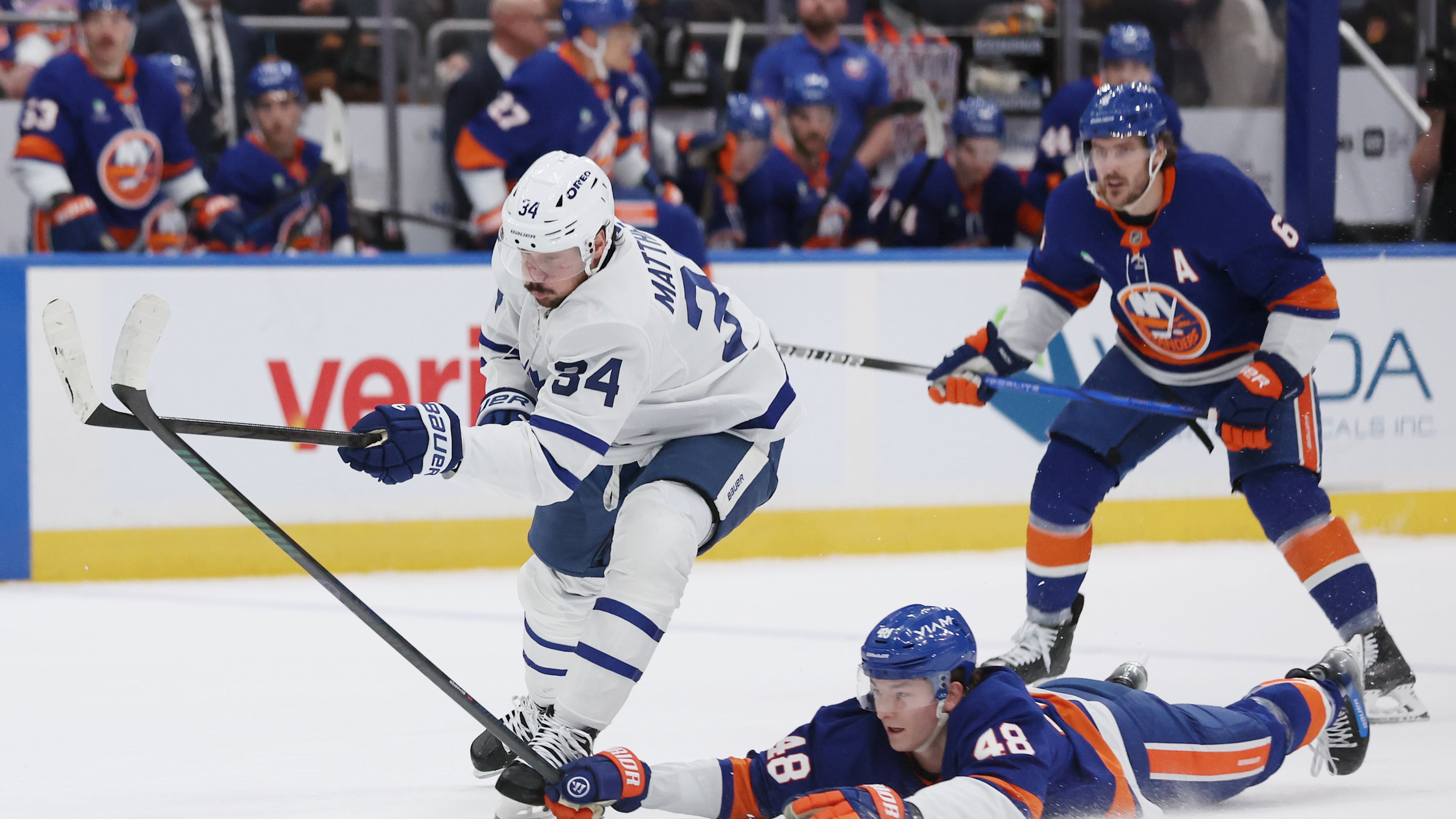 New York Islanders' Matthew Schaefer (48) reaches for the puck against Toronto Maple Leafs center Auston Matthews (34) during the first period of an NHL hockey game, Saturday, Jan. 3, 2026, in New York. (AP Photo/Heather Khalifa)