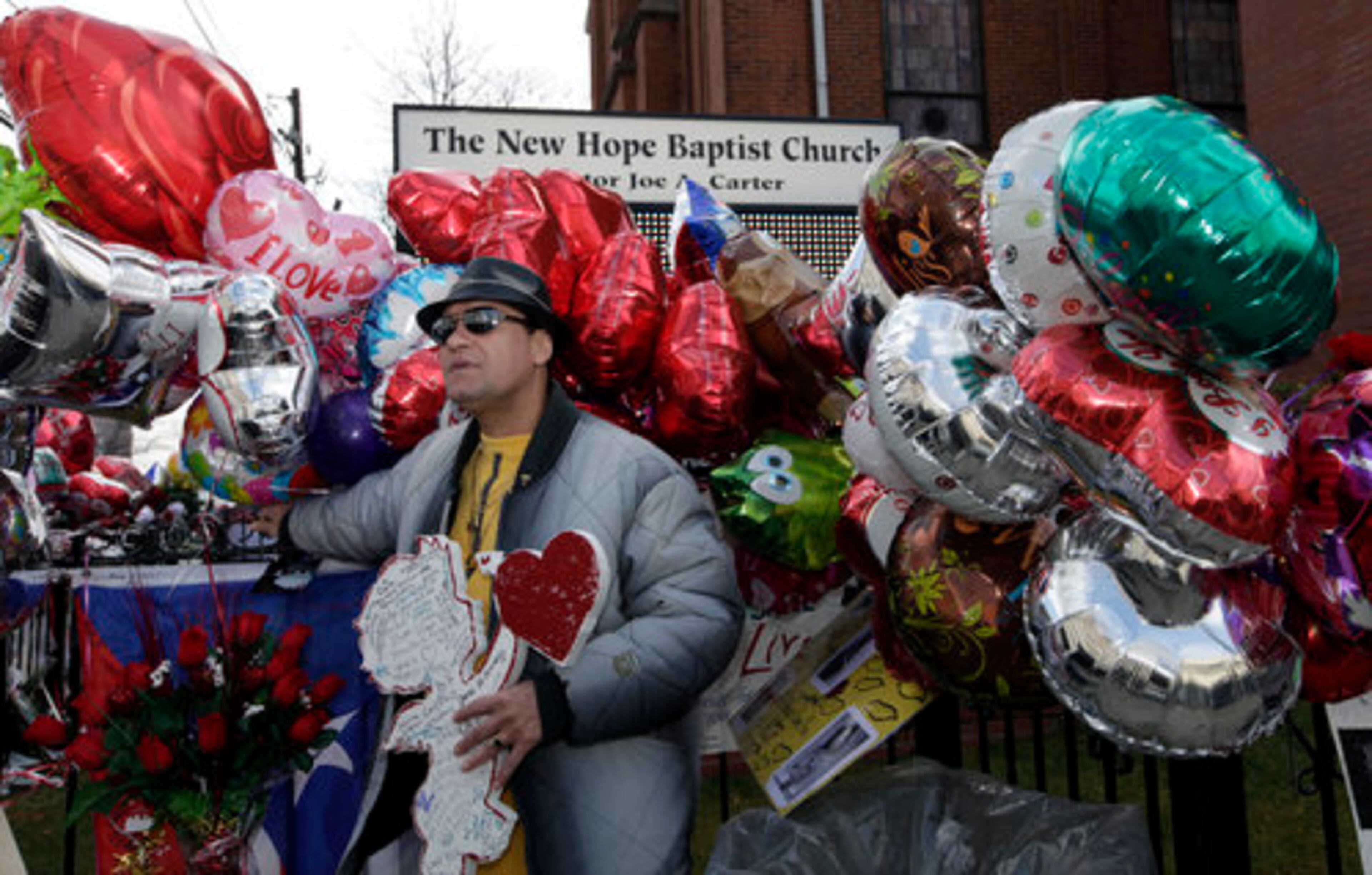 A man holds a signed Cupid cut-out as he stands at a memorial to Whitney Houston outside New Hope Baptist Church in Newark, N.J., Friday, Feb. 17, 2012. Houston's funeral will be held Saturday, Feb. 18, at New Hope where she sang in the choir as a girl.