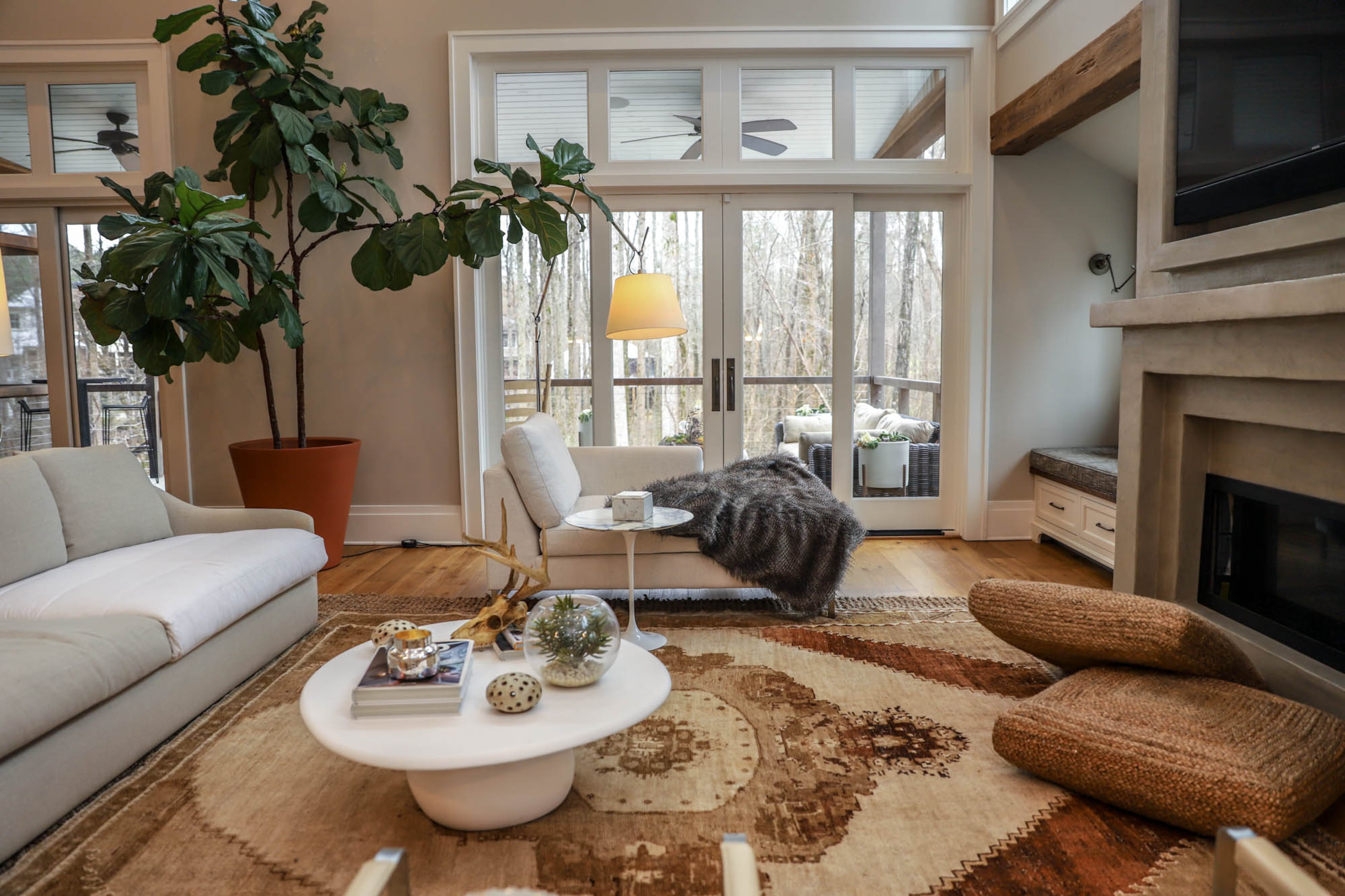A large fiddle-leaf fig brings color and a touch of nature to the neutral-toned living room. An antique rug from Mathews Furniture + Design is layered on a jute rug from Overstock.com.