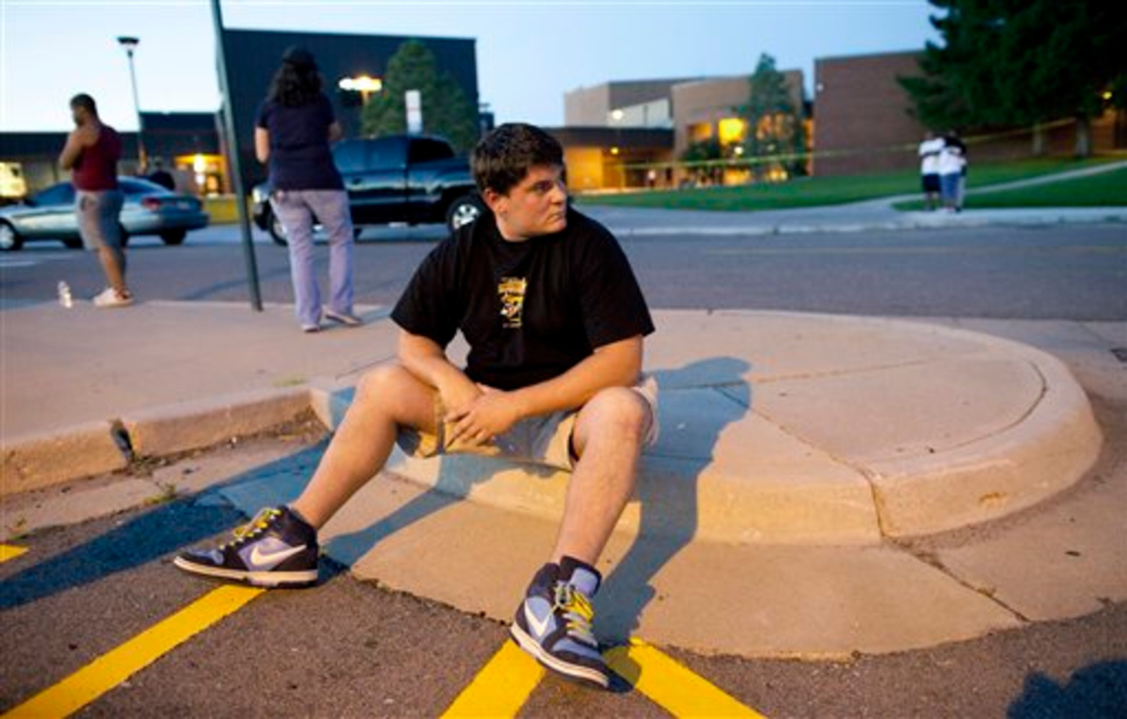 Eyewitness Chandler Brannon, 25, sits outside Gateway High School where witnesses were brought for questioning after a shooting at a movie theater showing the Batman movie "The Dark Knight Rises," Friday, July 20, 2012 in Aurora. A gunman wearing a gas mask set off an unknown gas and fired into the crowded movie theater killing 12 people and injuring at least 50 others, authorities said. (AP Photo/Barry Gutierrez)