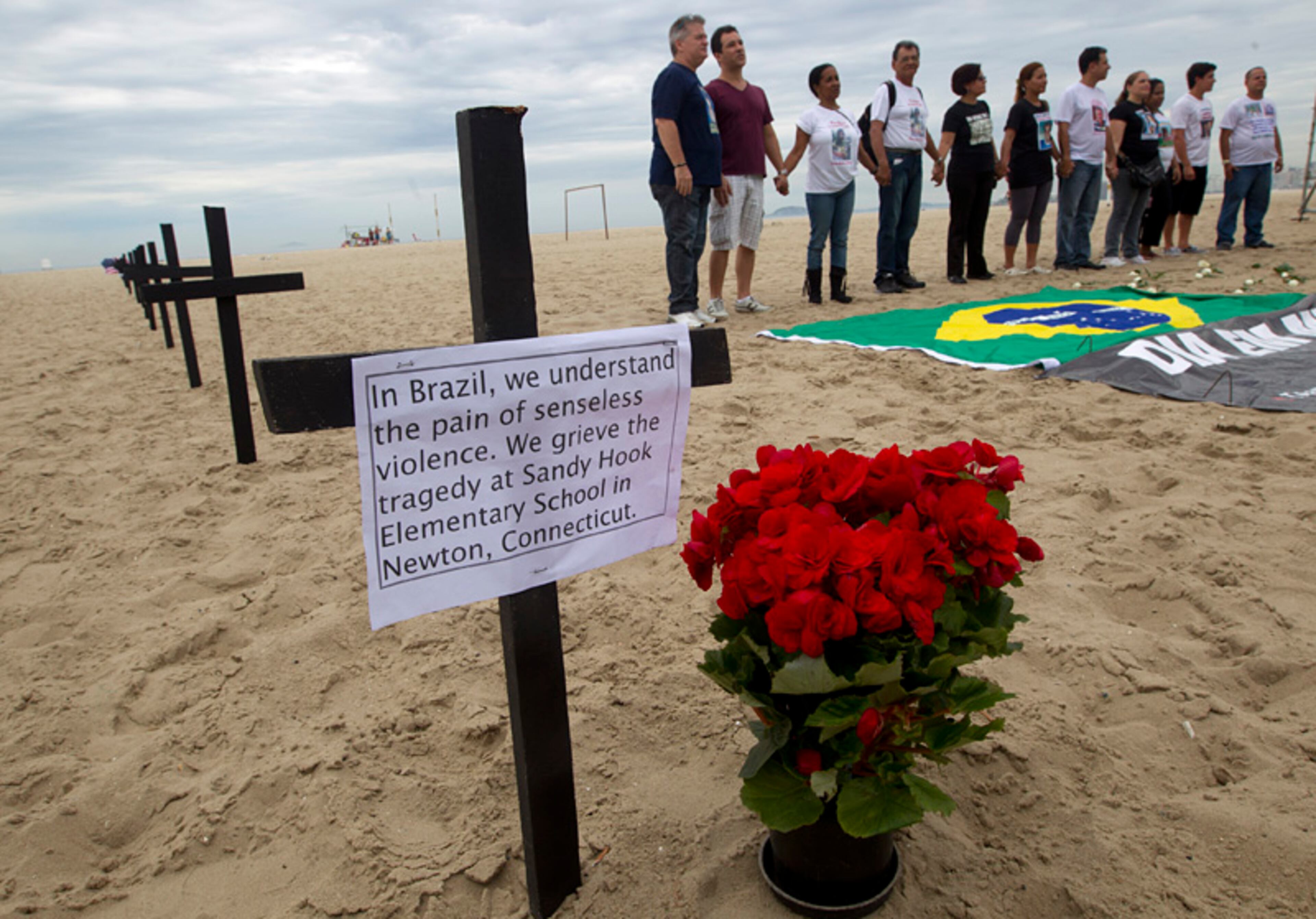 Relatives of victims of violent crimes stand near crosses in honor of the school shooting victims in Newtown, Conn., at the Copacabana Beach, in Rio de Janeiro, Saturday, Dec. 15, 2012.
