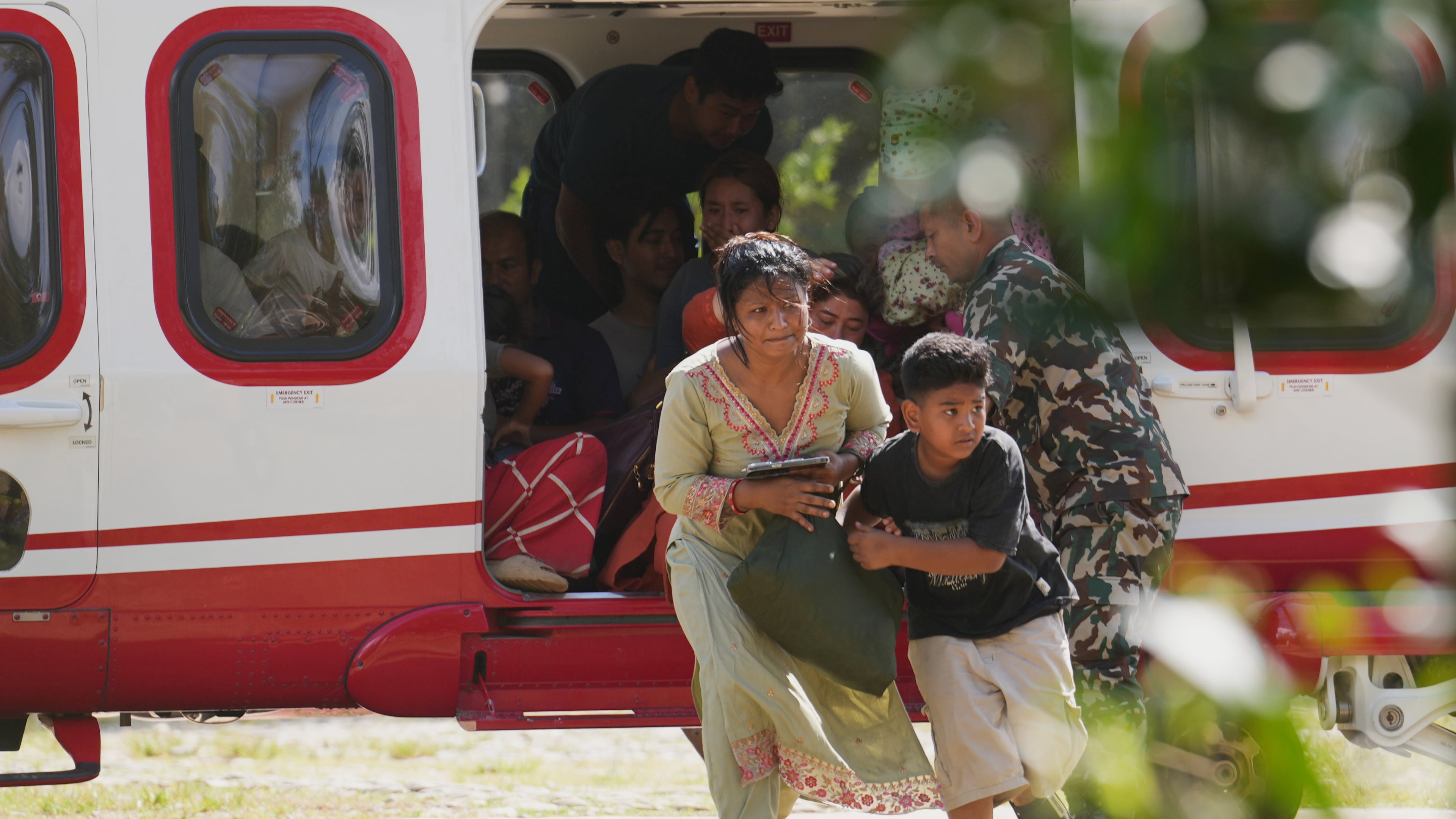 Army soldiers help a family disembark from a helicopter after they are rescued from an area affected by flash flooding in Nepal's Nuwakot district, Friday, Aug. 28, 2026. (AP Photo/Rajesh Kumar Singh)