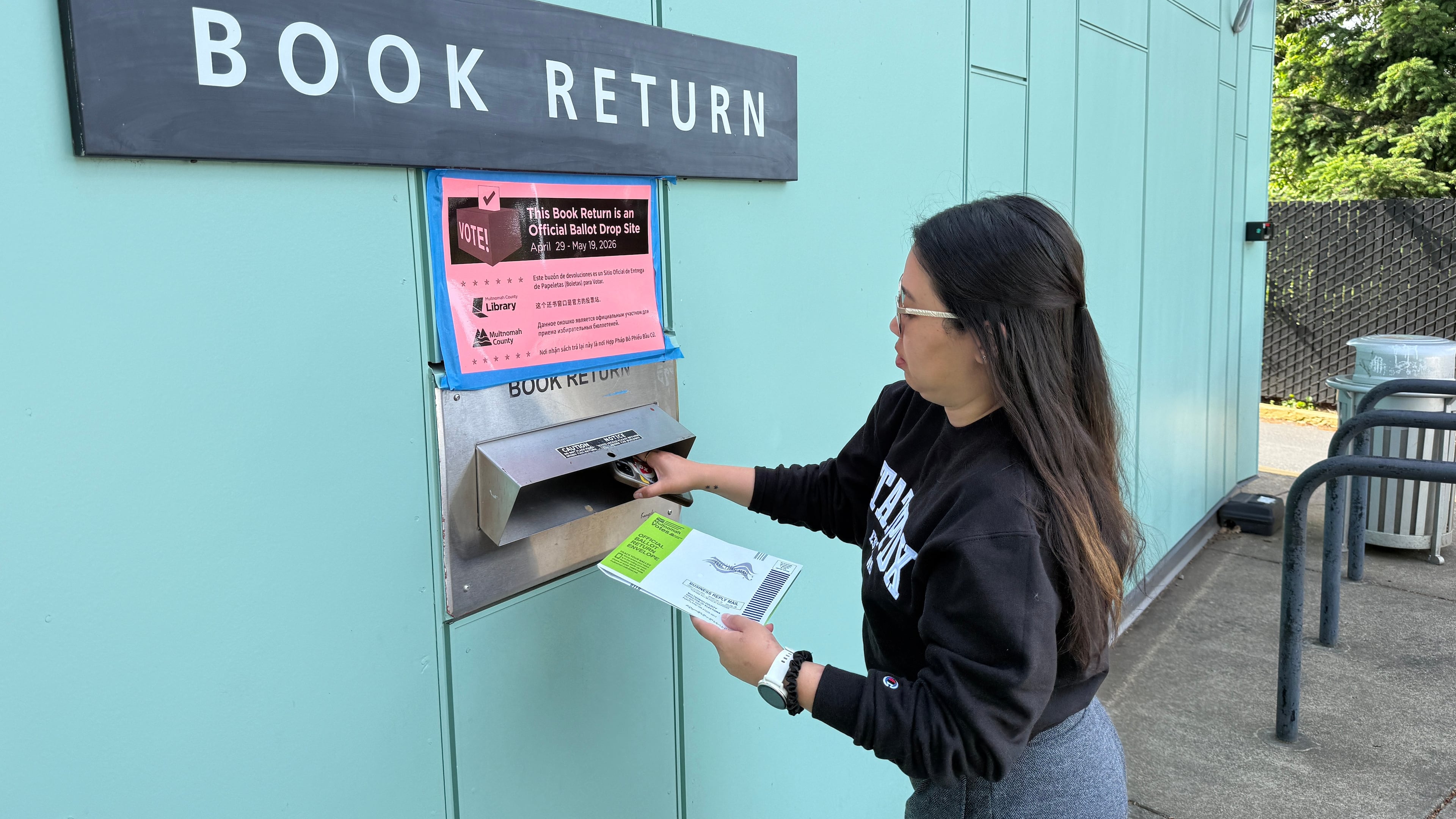 A voter drops off their ballot at a library in Portland, Ore. serving as a ballot dropbox site as Oregon held primary elections on May 19, 2026. (AP Photo/Claire Rush)