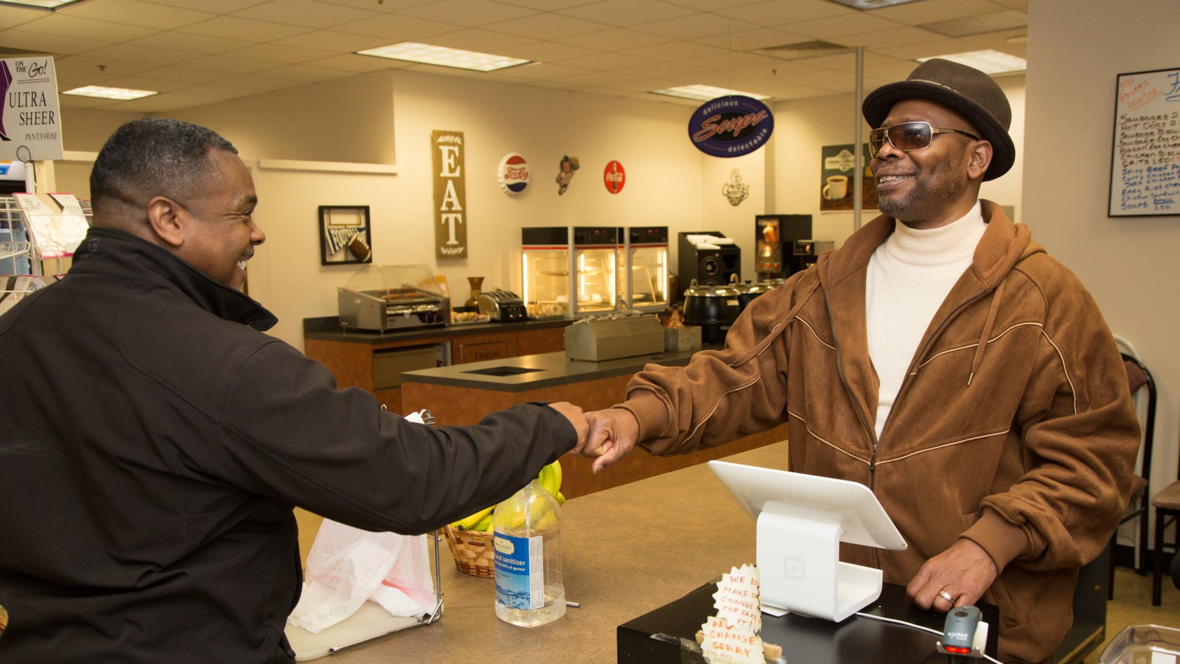 Anthony Brewer (left) fist pumps Eddie Mial, who runs a snack shop in the basement of the DeKalb County Courthouse in Decatur. The gregarious Mial greets every customer who comes in the store. (Photo by Phil Skinner)