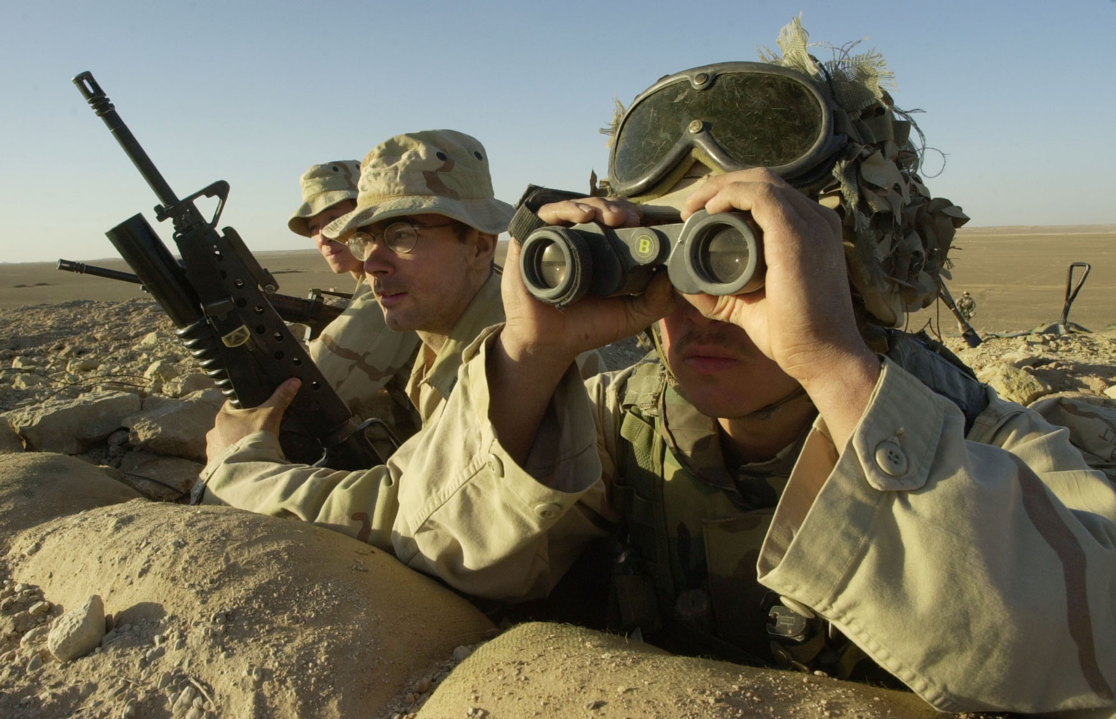 Marine LCPL Carlos Romero, right, of Long Beach, Calif., uses binoculars to check the horizon from his fighting hole near Camp Rhino in Southern Afghanistan on Sunday, Dec. 9, 2001. At left is LCPL Bryce Collins of Juneau, Alaska. At center is Cpl. David Lacerte of Montegut, La.. The Marines with the 15th Marine Expeditionary Unit from Camp Pendleton, Calif. (AP Photo/Dave Martin, POOL)