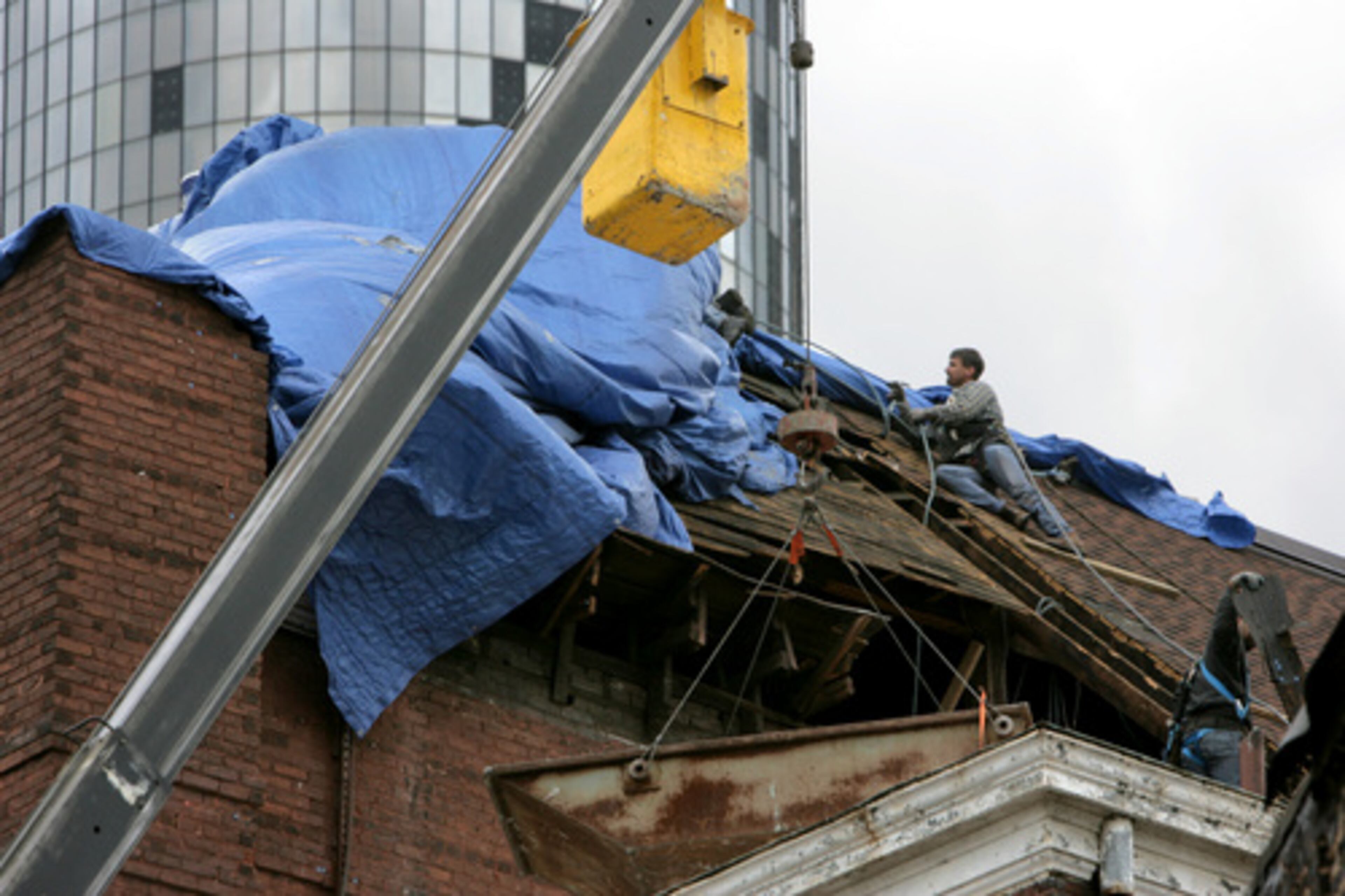 Work on roof of the Tabernacle with the Westin Peachtree Plaza Hotel in background. Both were damaged by the tornado