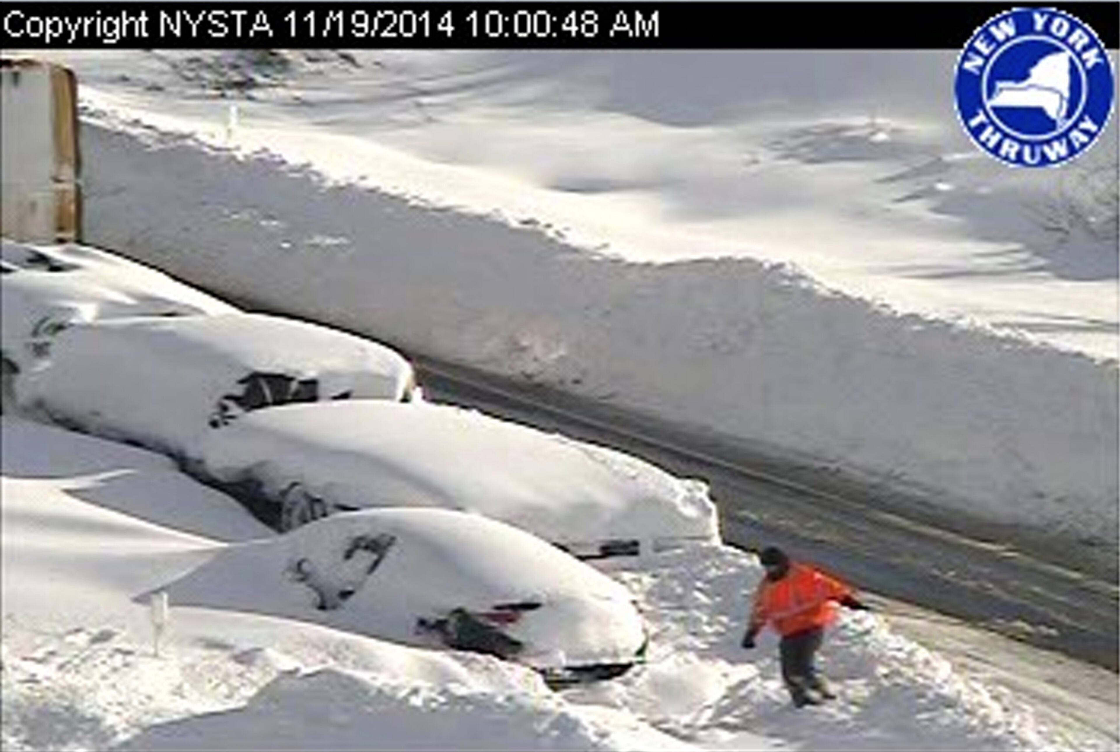 In this photo from a surveillance camera operated by the New York State Thruway Authority, a person climbs through piles of snow next to abandoned vehicles on the Thruway, near Lackawanna, N.Y., Wednesday, Nov. 19, 2014. A 132-mile stretch of the state Thruway in western New York remains closed as authorities continue their efforts to rescue motorists stranded on a Buffalo-area section of the highway. (AP Photo/New York State Thruway Authority)