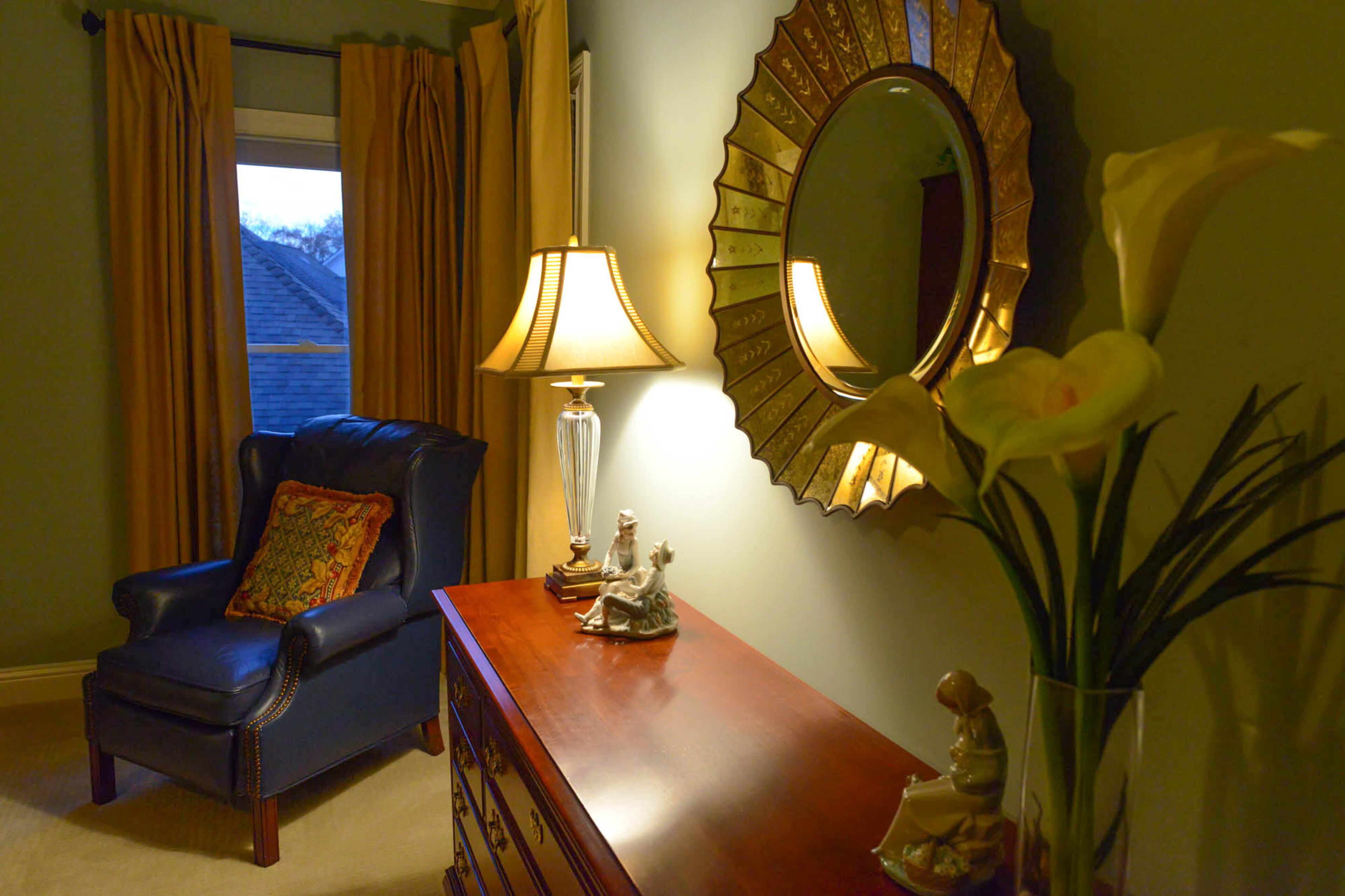 Figurines, flowers and a mirror with a sunburst shape are paired with custom window treatments by Lori Harbrecht in the master suite. The furniture is from Bassett.