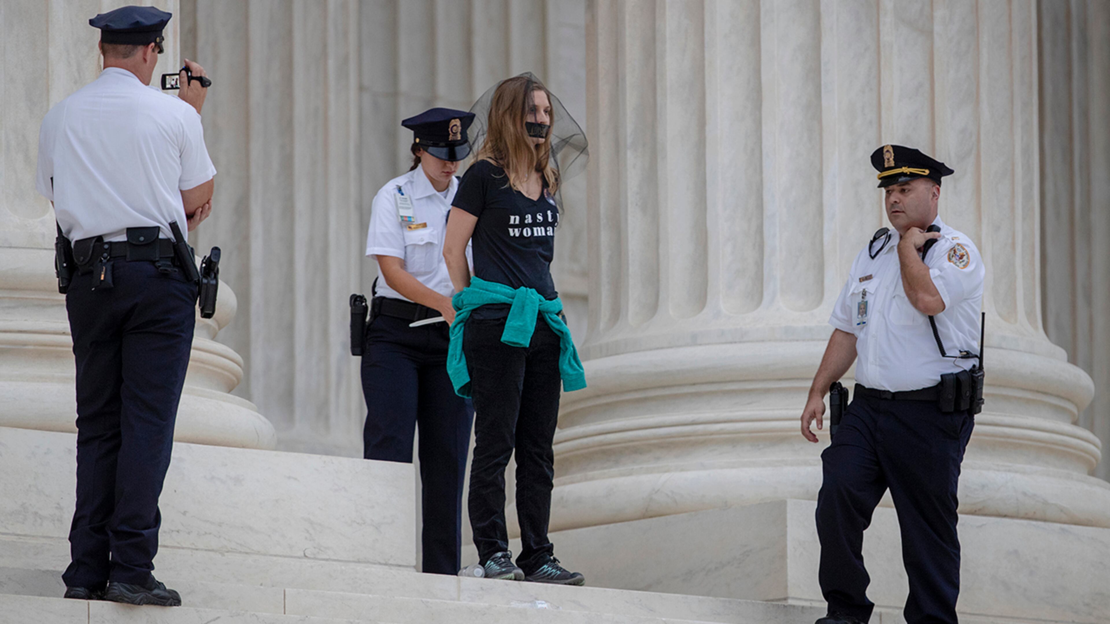 An activist is arrested on the steps of the Supreme Court Building as demonstrators protested the confirmation of Brett Kavanaugh as the high court's newest justice, in Washington, Saturday, Oct. 6, 2018. Kavanaugh took the oath inside the building after the bitterly polarized U.S. Senate narrowly confirmed him, delivering an election-season triumph to President Donald Trump that could swing the court rightward for a generation. (AP Photo/J. Scott Applewhite)
