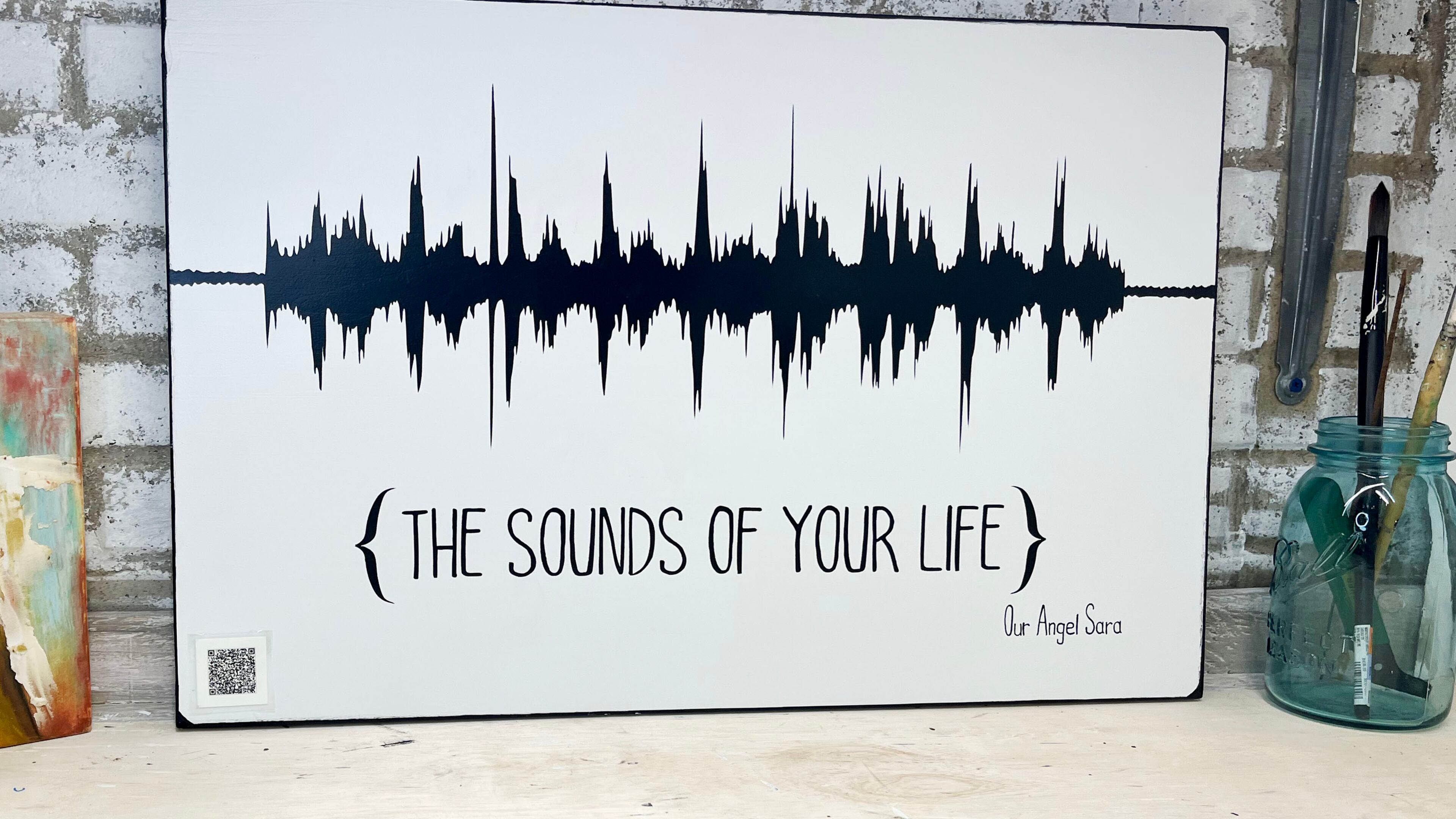 The soundwave image is created from an audio or video file sent to the artist. The “magic” is the QR code that plays back the original message or sound.