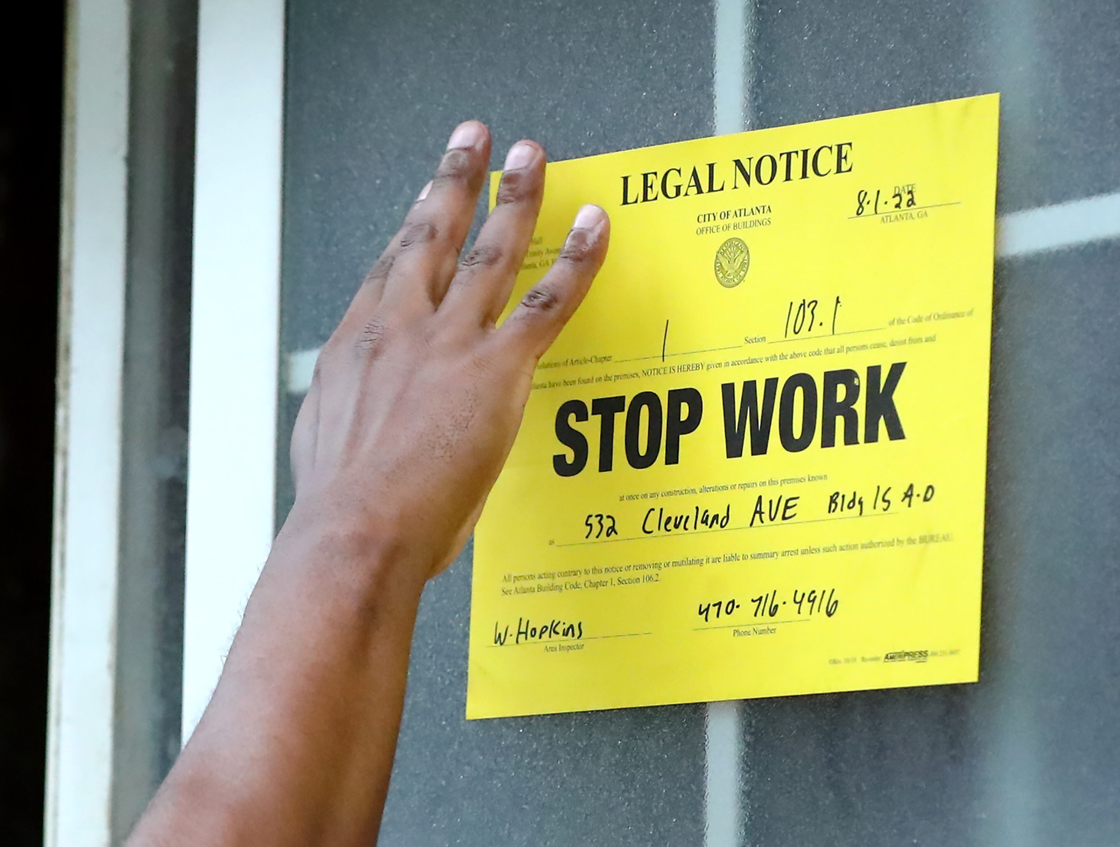 A City of Atlanta zoning employee posts a stop work legal notice on the window of a burned out apartment unit during a sweep of Pavilion Place apartments on Monday. The state Department of Community Affairs said they worked with the city on Monday’s inspections and it could take up to two weeks for the state to coordinate their list of findings with the city. (Curtis Compton / Curtis Compton@ajc.com)