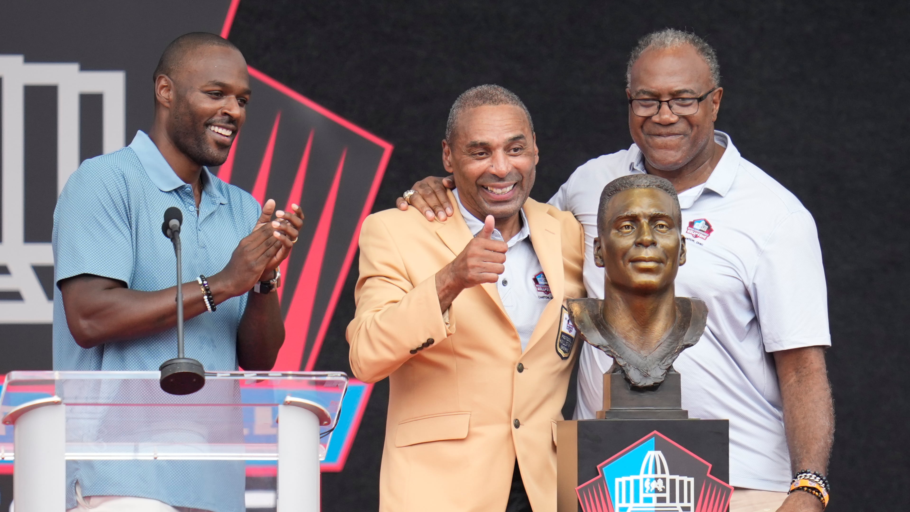 Former NFL player Roger Craig, center, unveils his bust with son, Roderick Craig, left, and Jamie Williams during the Pro Football Hall of Fame induction ceremony at the Pro Football Hall of Fame, in Canton, Ohio, Saturday, Aug. 8, 2026. (AP Photo/Sue Ogrocki)