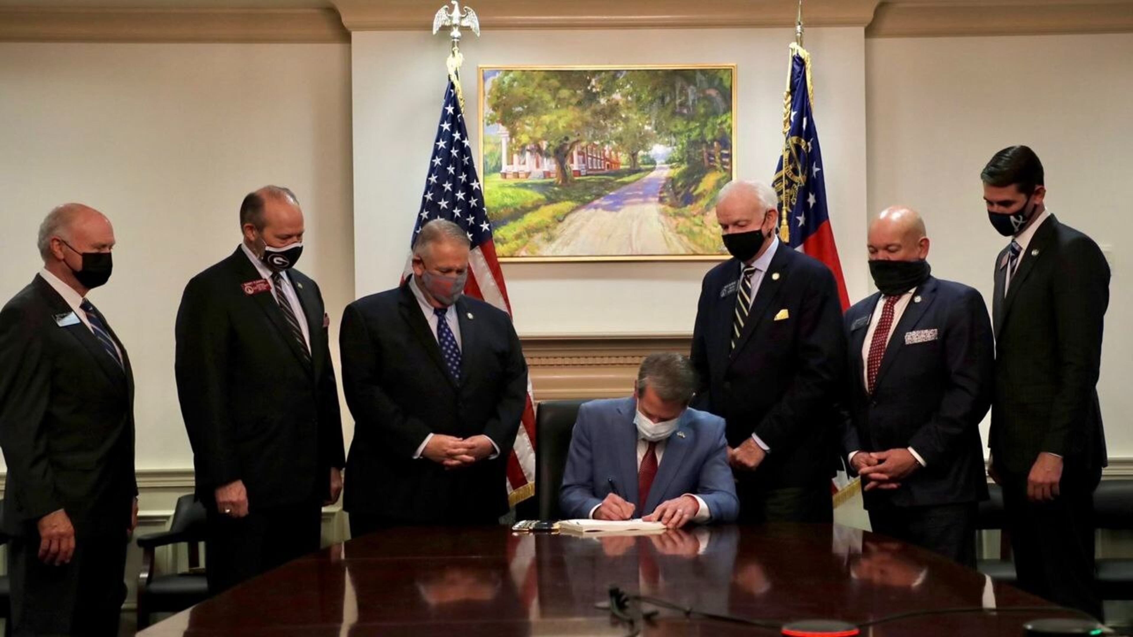 Gov. Brian Kemps signs the election bill as legislators and the lieutenant governor look on March 25, 2021, at the governor's office.