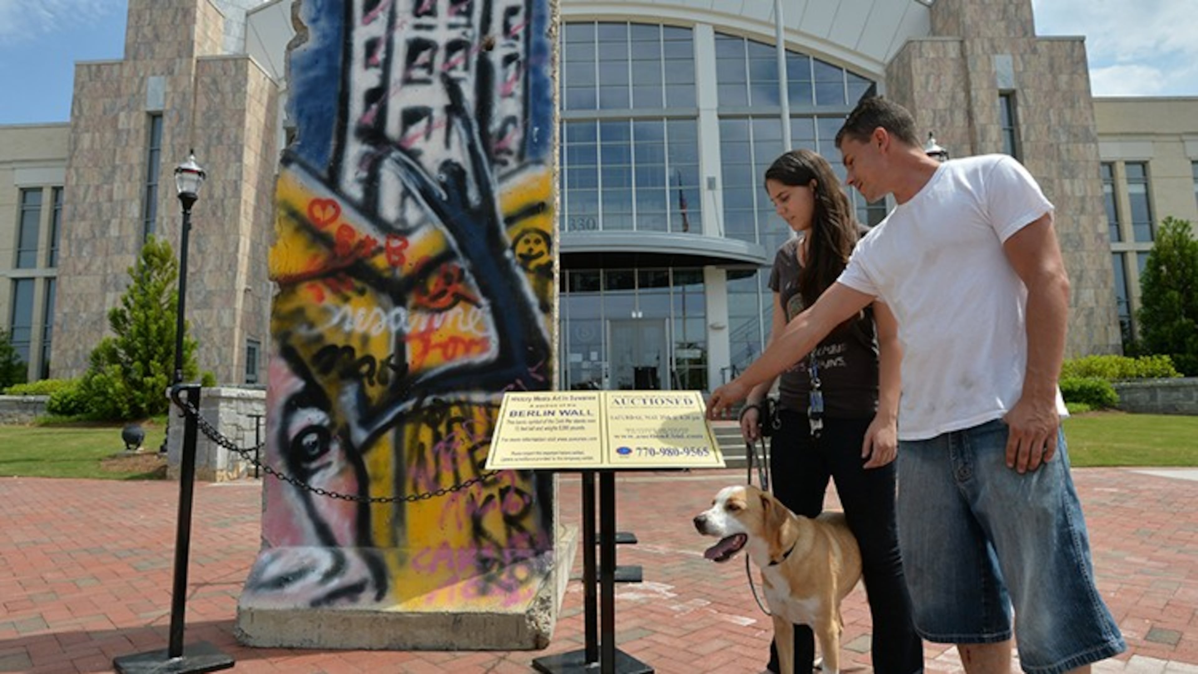 Dianne Meuse and her friend, Adam Pietroski, both of Buford, check out a 12-foot-tall section of the Berlin Wall on display in front of Suwanee City Hall. AJC File