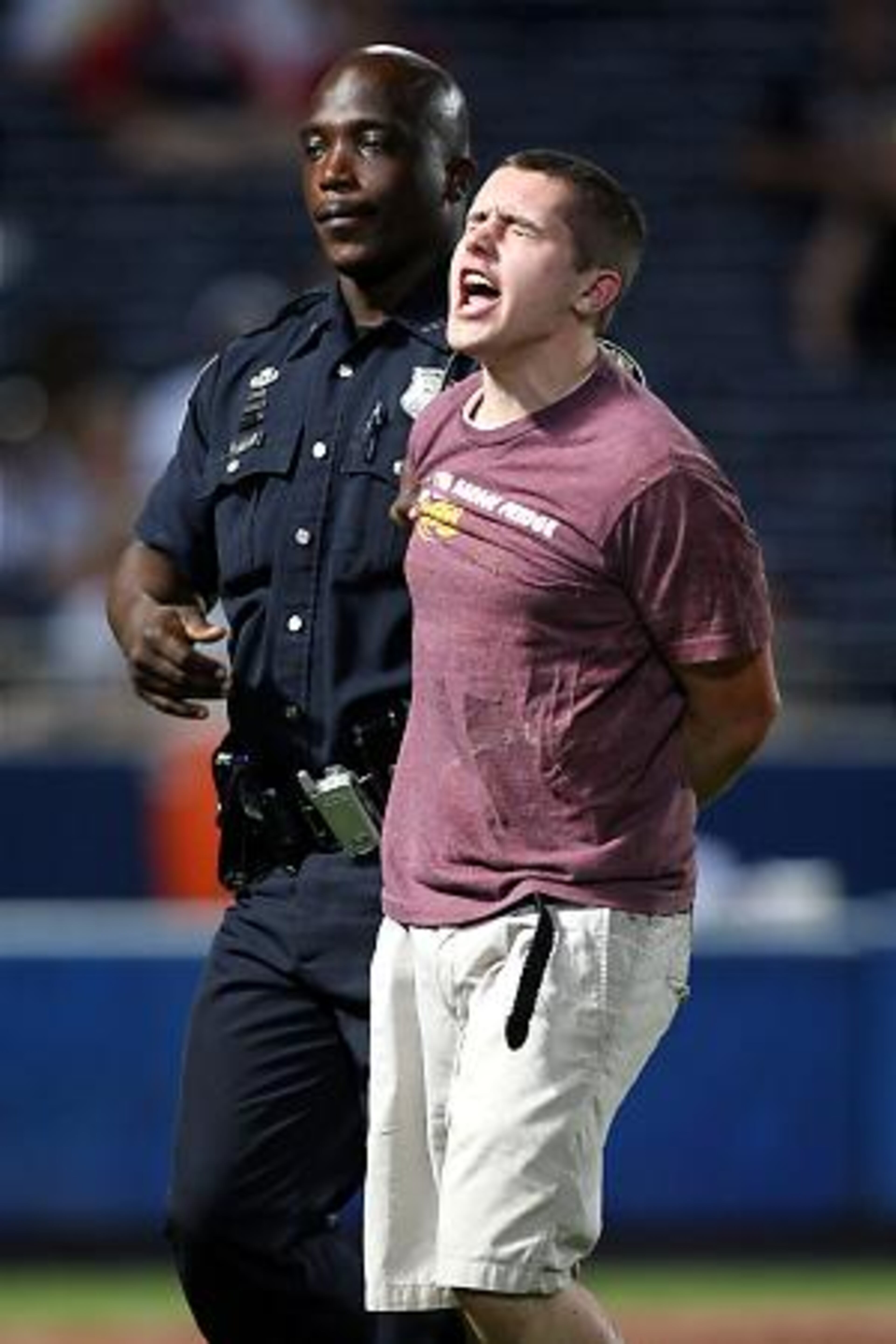 A man yells "I love the Braves" as he is taken into police custody after charging the field in the ninth inning.