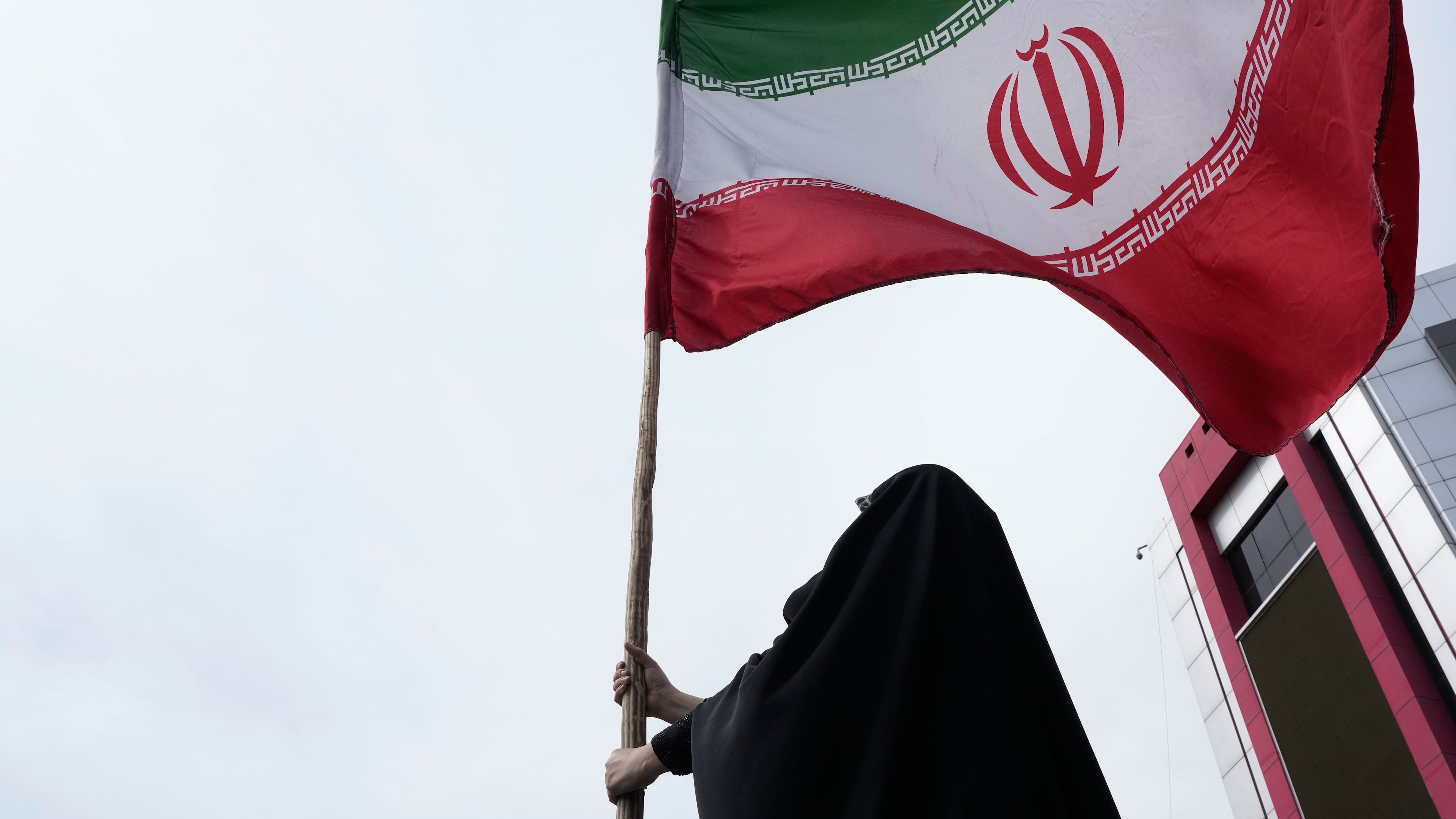 A woman holds an Iranian flag for a pro-government campaign in downtown Tehran, Iran, Saturday, April 25, 2026. (AP Photo/Vahid Salemi)