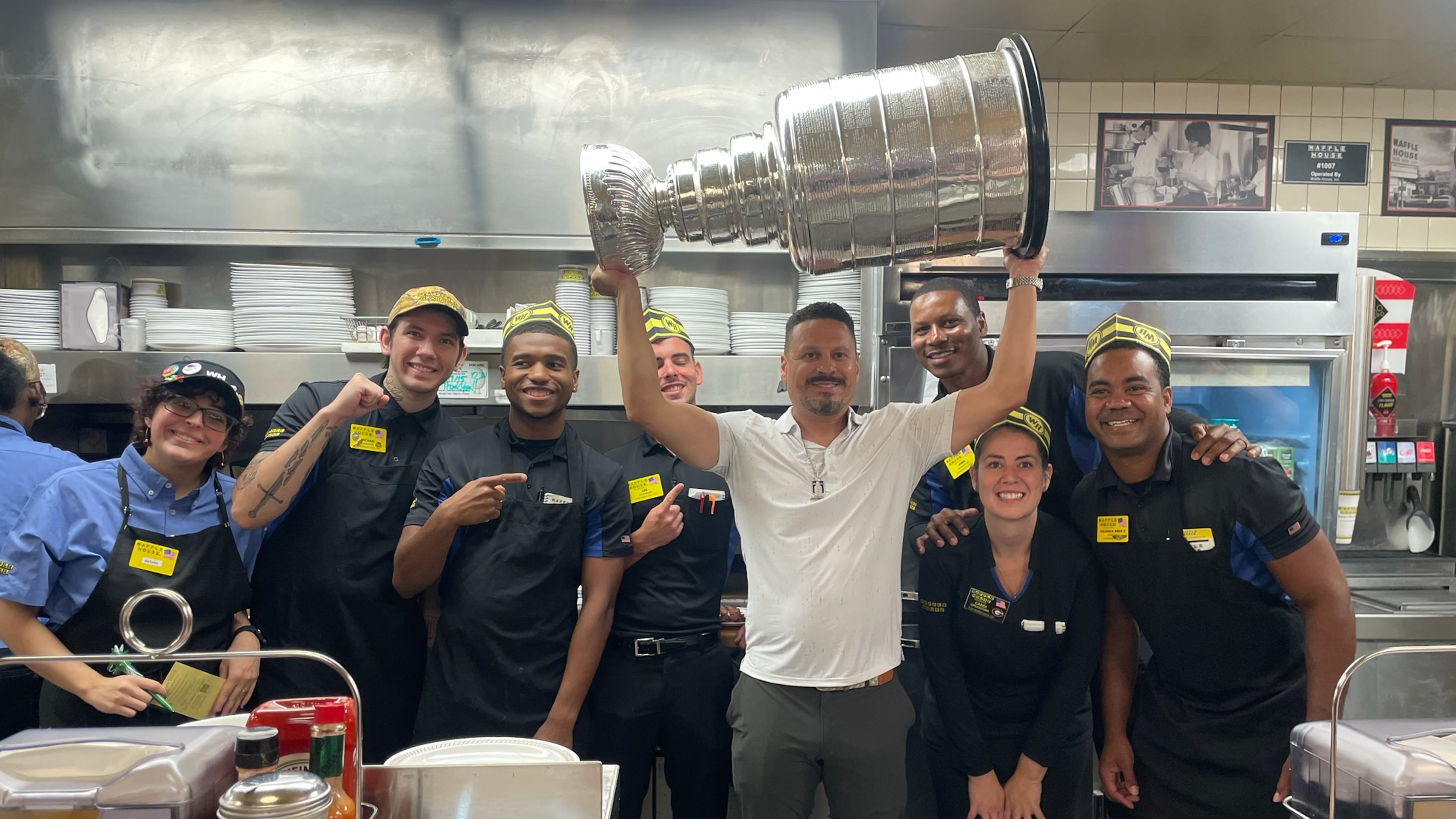 Mike Huff, VP of player engagement with the NHL champion Florida Panthers and a former Atlantan, holds the Stanley Cup aloft with employees at a Buckhead Waffle House on July 15, 2025. Allowed one day with the treasured trophy, Huff created an itinerary around metro Atlanta to share it with various groups of people. (Courtesy of Mike Huff)