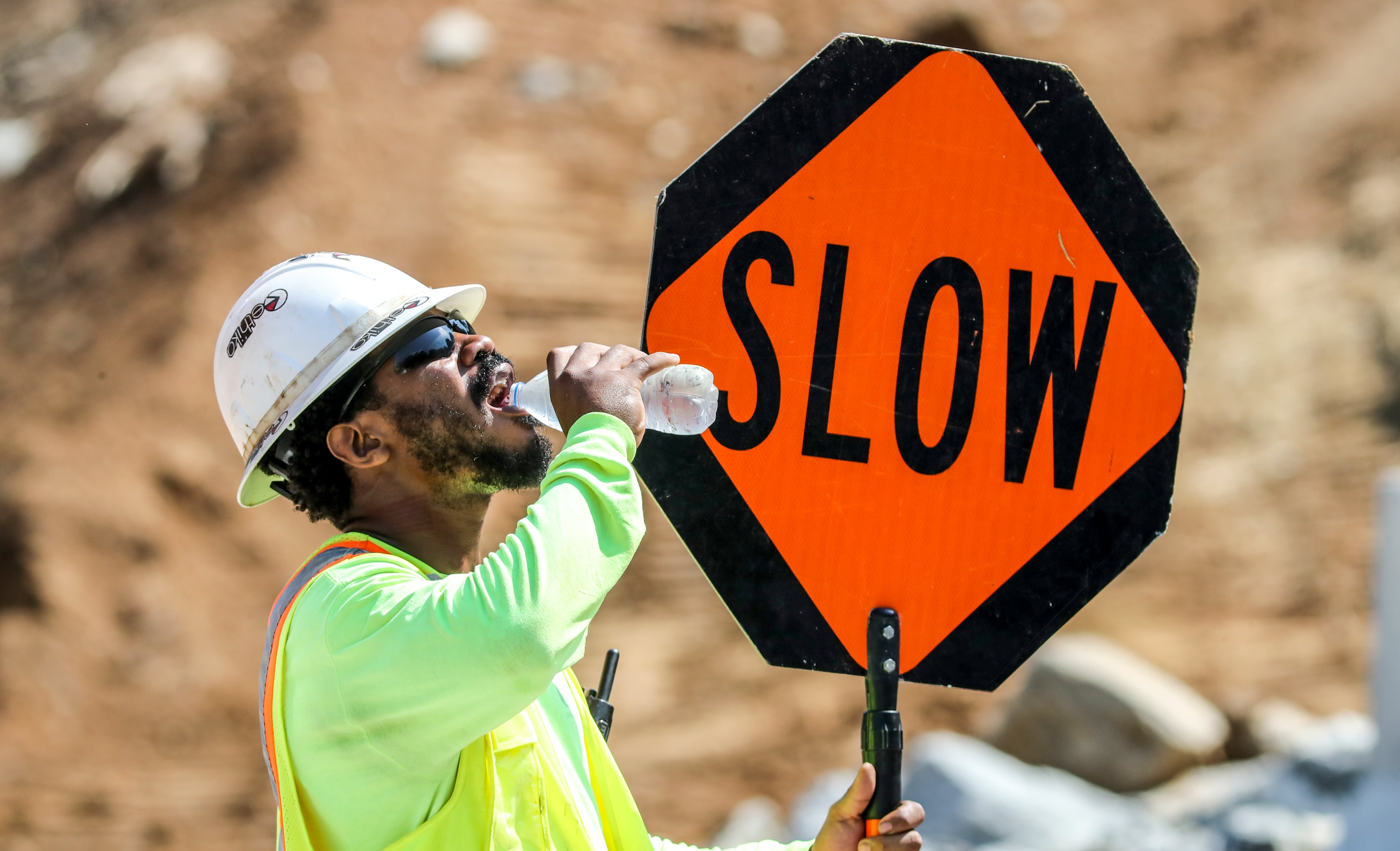 People who work outside during extreme heat, such as Deangelo Sanford, need to be sure to stay hydrated throughout the day, experts say. (John Spink/AJC 2022)