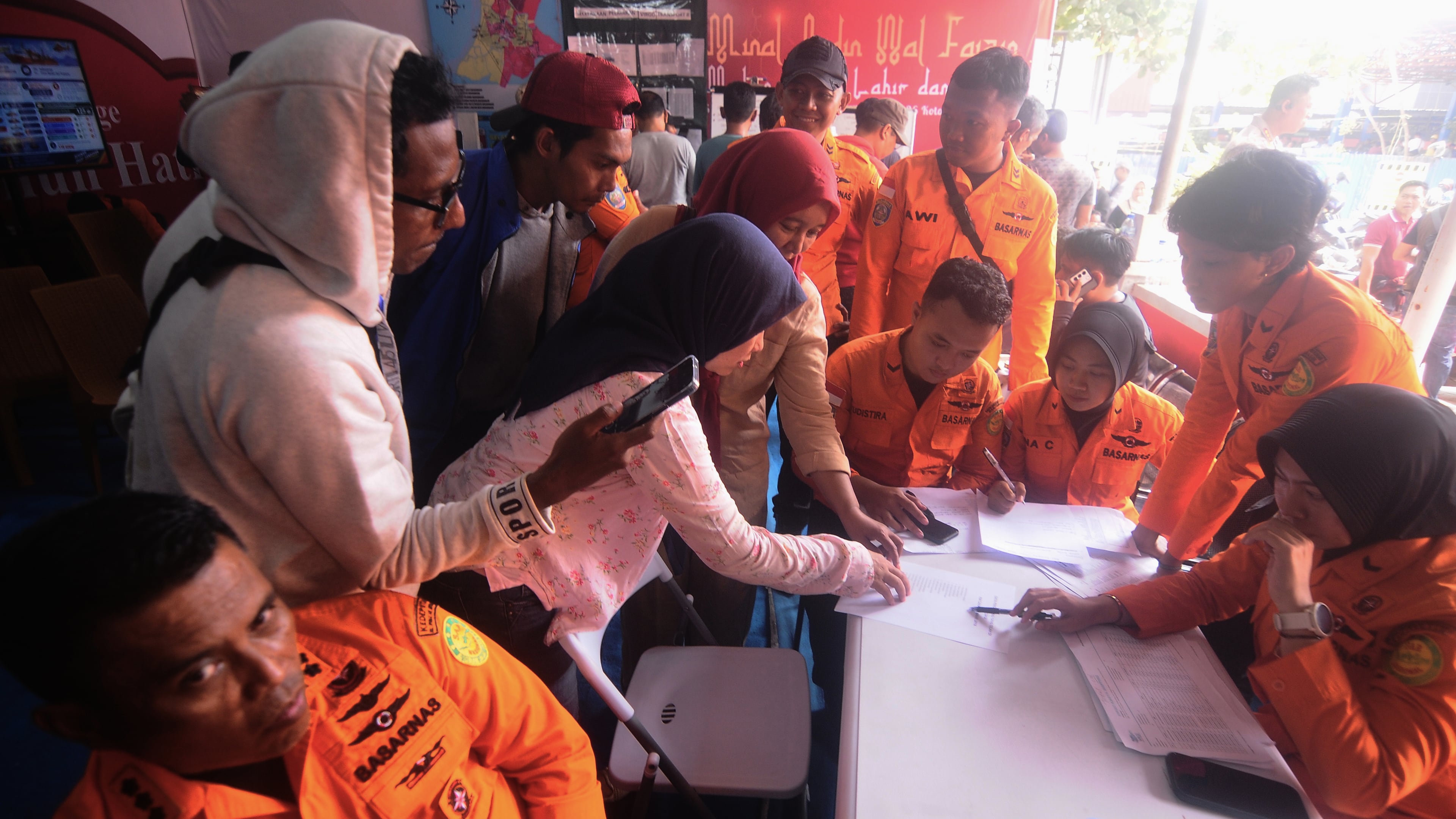 People look for the names of their family members on a passenger list after a ferry overturned in bad weather in the Java Sea, at the rescuers command center in Banjarmasin, South Kalimantan, Indonesia, Sunday, Sept. 13, 2026. (AP Photo/Iman Satria)
