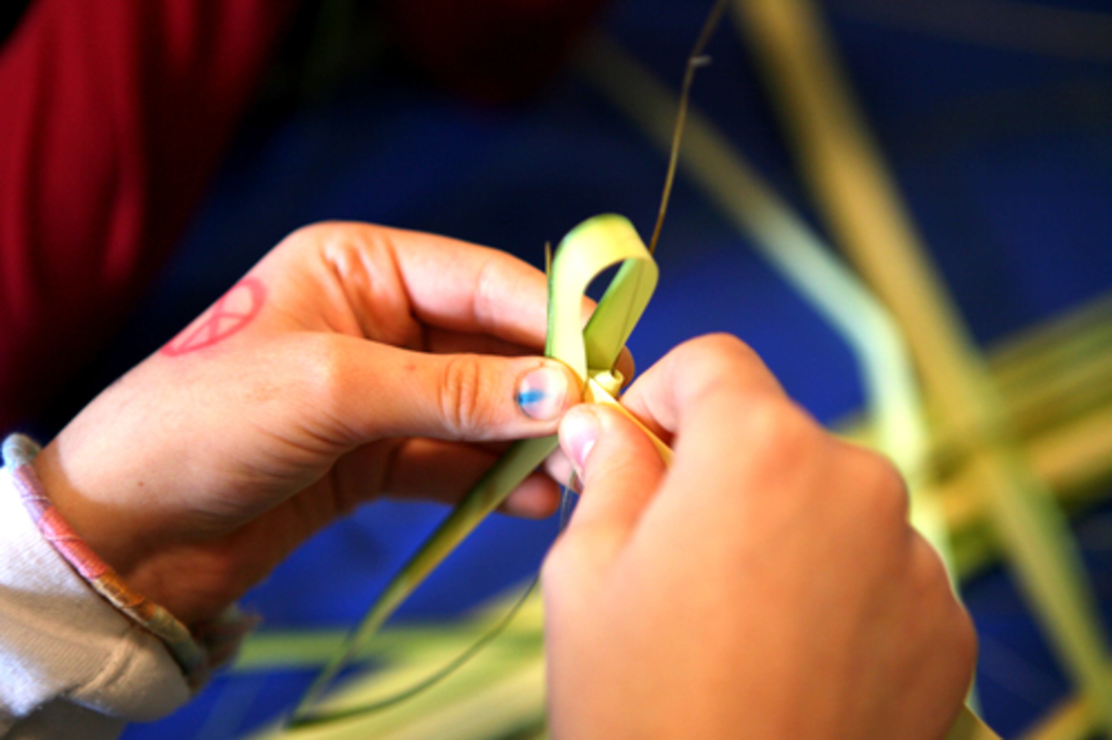 Children make crosses from palm leaves in preperation for Palm Sunday at Saints Raphael, Nicholas and Irene's Greek Orthodox Church in Cumming on Sunday.