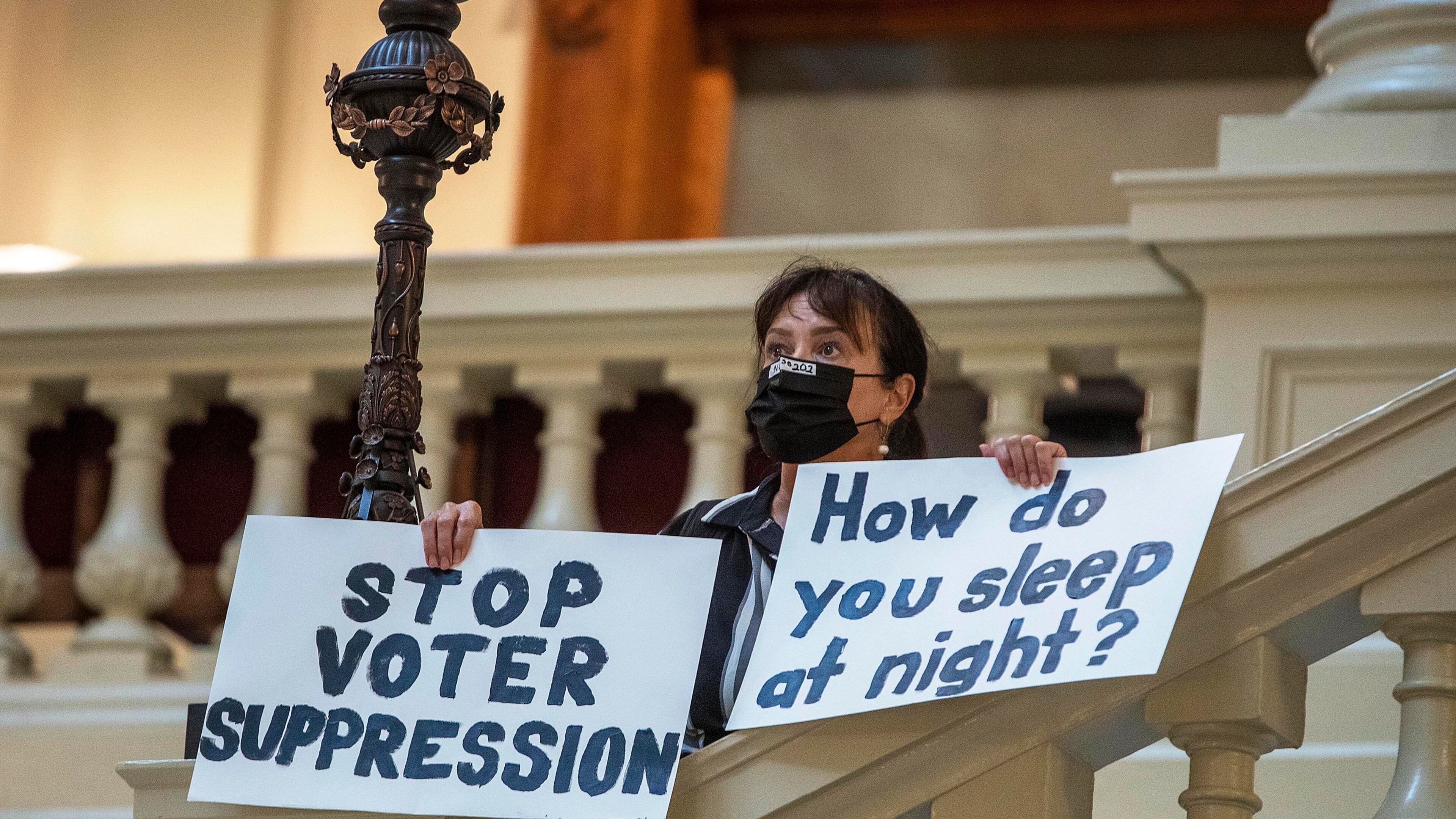 Ann White of Roswell holds protest signs on the North Wing stairs of the Georgia State Capitol building on day 38 of the legislative session in Atlanta, Thursday, March 25, 2021. "It ain't over yet," said White. "I look forward to going door-to-door working against everybody that voted for (SB 202)." SB 202 passed the House Chambers and was immediately transferred to the Senate Chambers. (Alyssa Pointer/Atlanta Journal-Constitution /TNS)