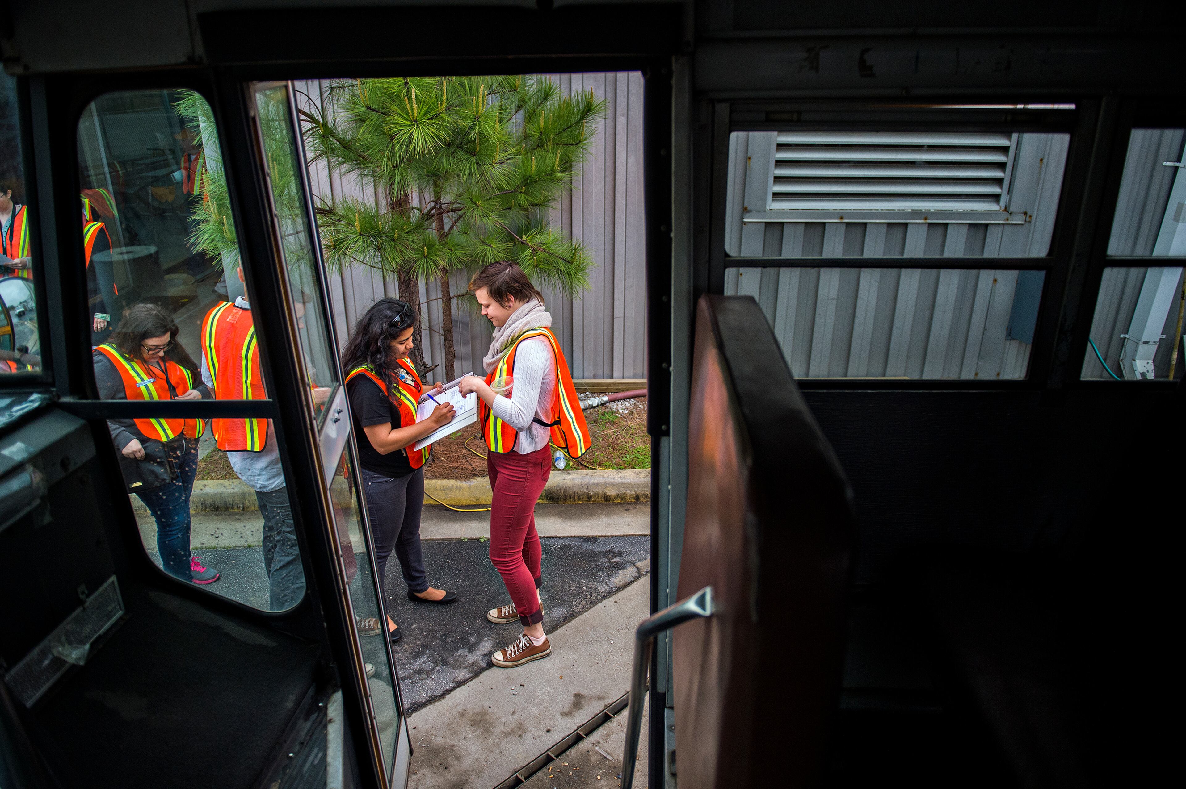 April 12, 2015 Doraville - Meyly Brizuela (center) signs a release form held by Emily Schreck (right) before piling onto a bus full of photographers that will take them into the General Motors assembly plant in Doraville during a #weloveatl photowalk on Sunday, April 12, 2015. 120 photographers were given special access to the plant that is being demolished and re-imagined into a multi-use space. JONATHAN PHILLIPS / SPECIAL