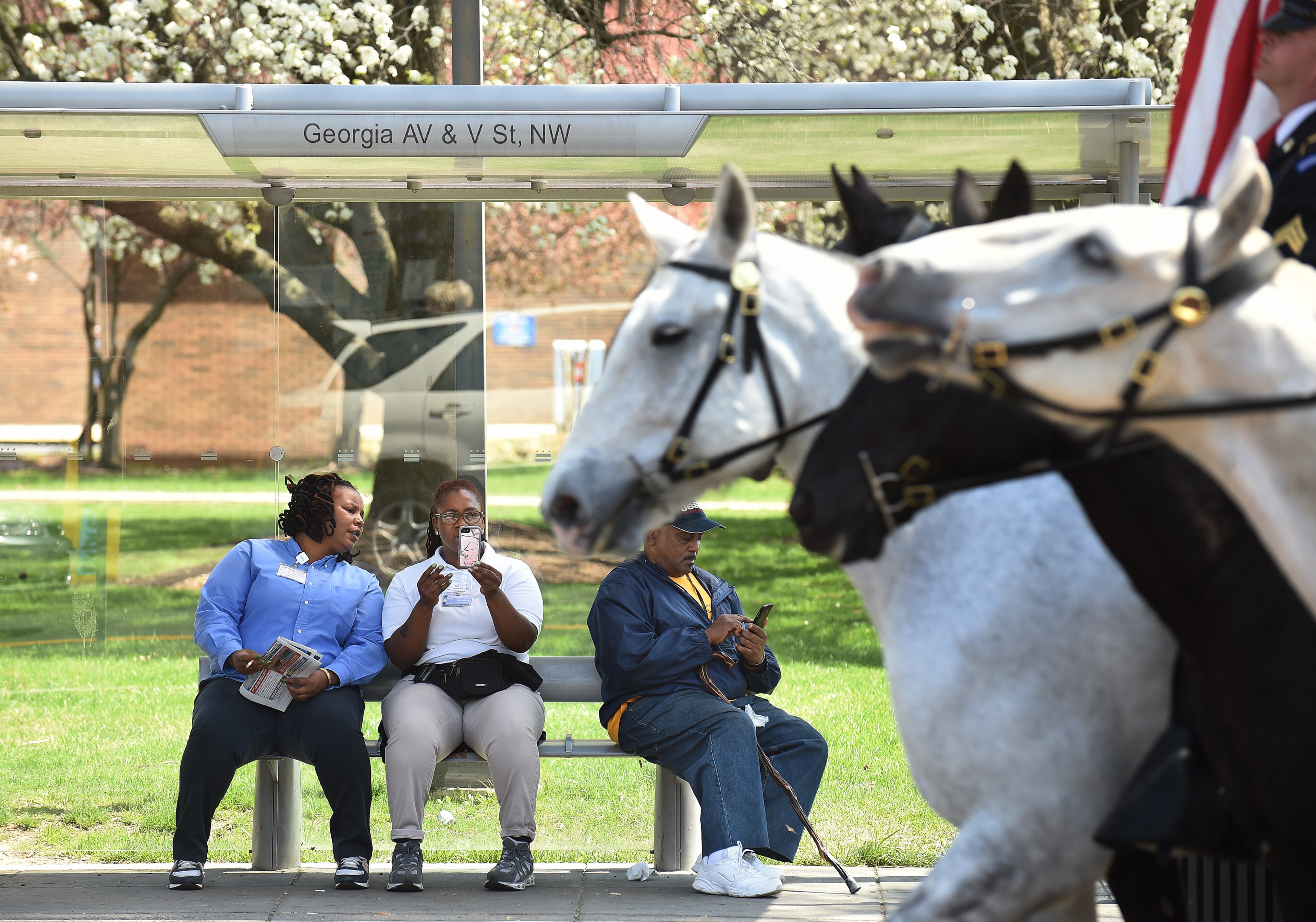 WASHINGTON, DC - APRIL 13: People at a bus stop watch a procession of riders taking part in an event to commemorate the 150th anniversary of President Abraham Lincoln's last visit to his cottage on Monday April 13, 2015 in Washington, DC. The riders started from Pennsylvania Ave. NW and 15th St. NW to Lincoln's Cottage. (Photo by Matt McClain/ The Washington Post via Getty Images)