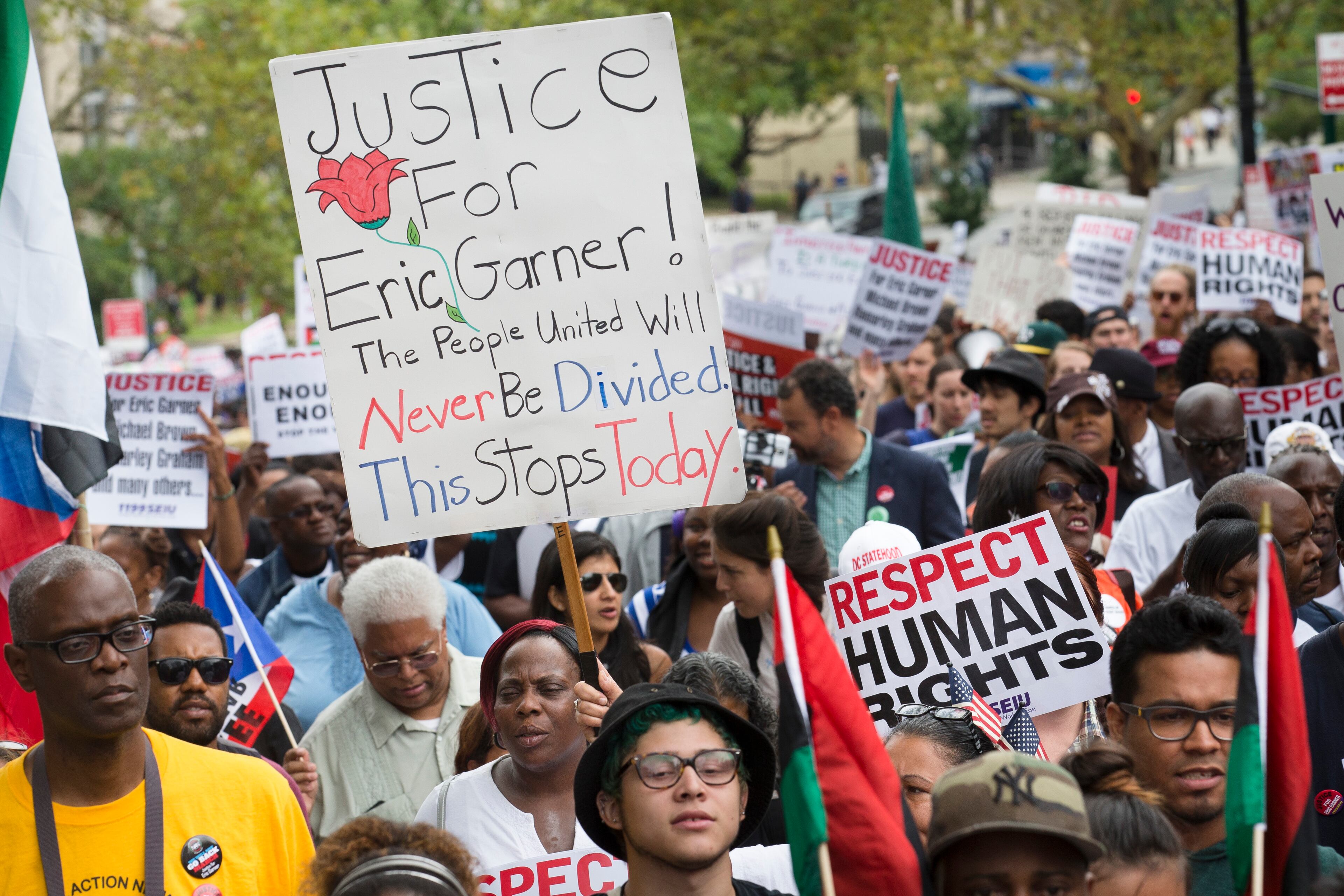 A demonstrator holds a sign that reads "Justice for Eric Garner" during a march to protest the death of Eric Garner, Saturday, Aug. 23, 2014, in the Staten Island borough of New York. The city medical examiner ruled that Garner, 43, died as a result of a police chokehold during an attempted arrest. The march was led by the Rev. Al Sharpton's National Action Network. (AP Photo/John Minchillo)