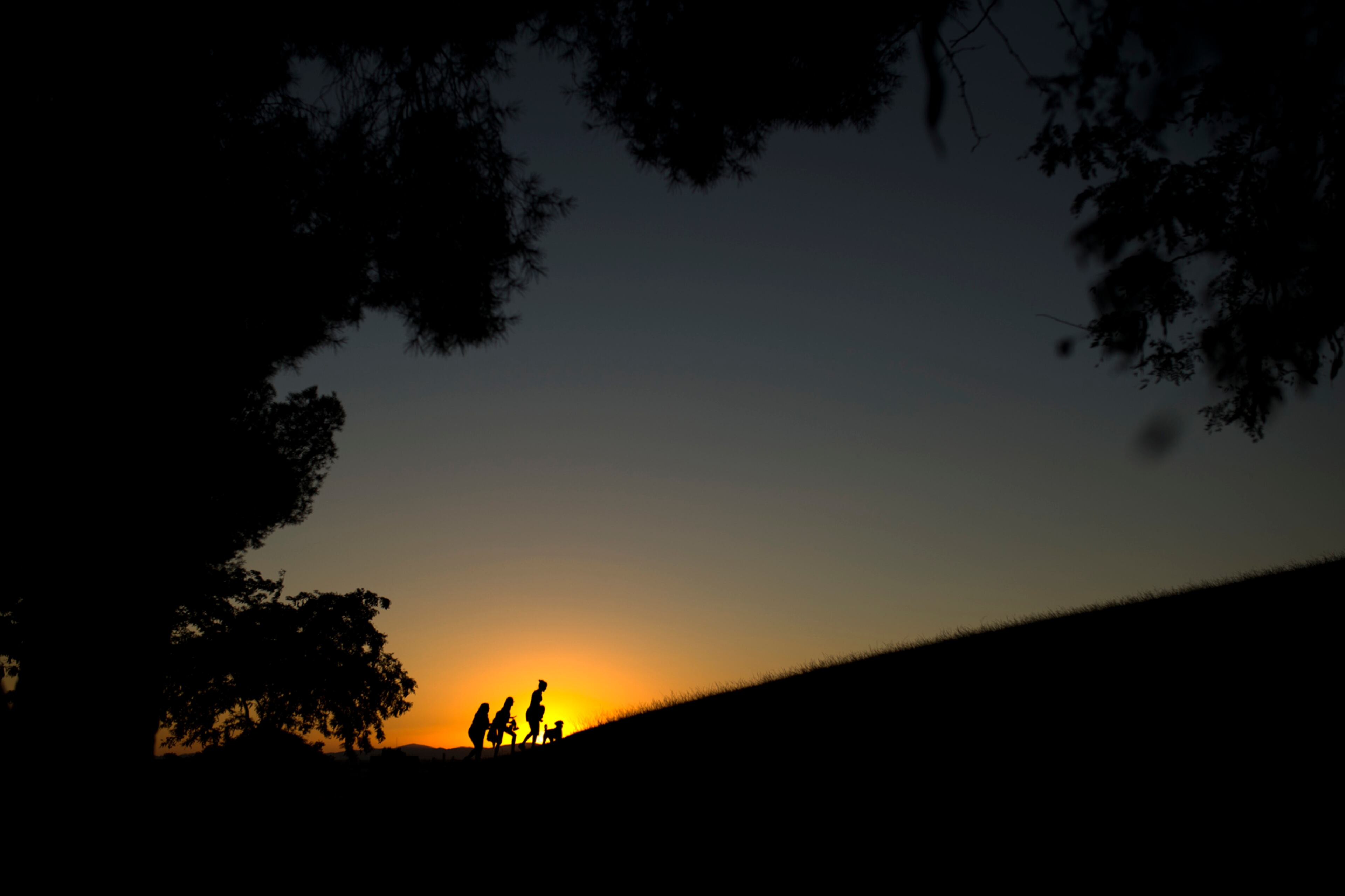 People walk atop a hill as the sun sets on a summer day at the Tio Pio park in Madrid, Monday, July 24, 2017. The park is a high viewpoint frequented mostly by locals due to its view of the Spanish capital skyline. (AP Photo/Francisco Seco)
