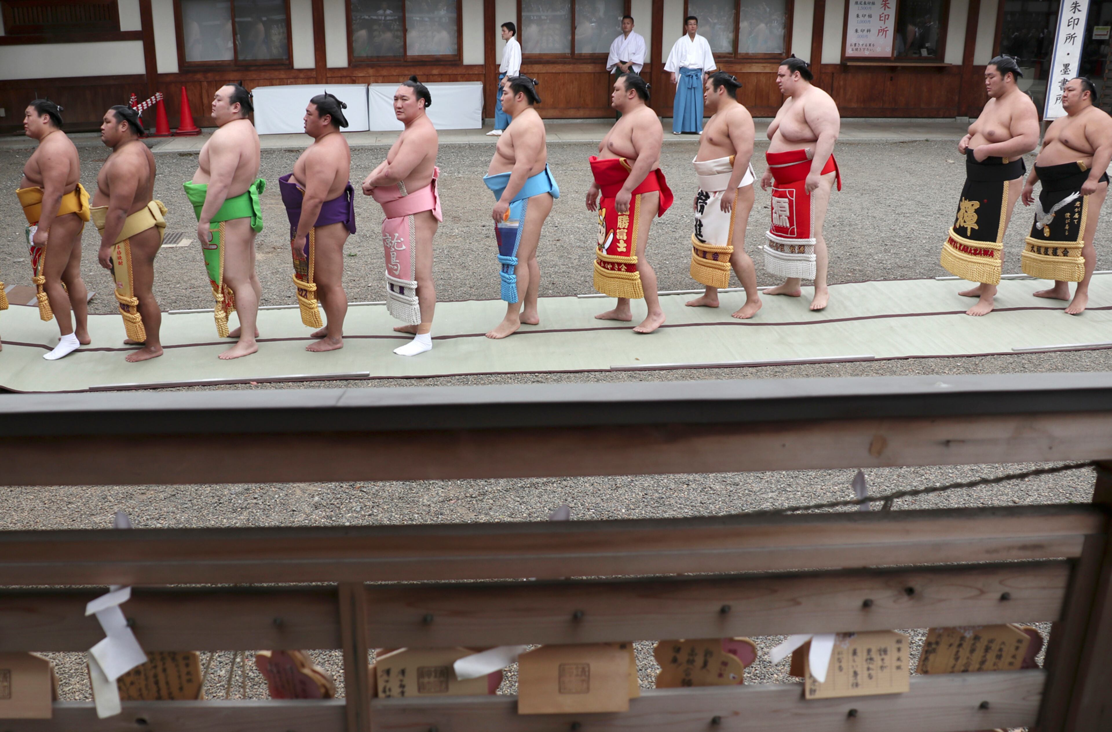 Sumo wrestlers stand in a line to offer prayers at the Yasukuni Shrine before the ritual sumo bouts held at the Shinto shrine in Tokyo, Monday, April 17, 2017. (AP Photo/Shizuo Kambayashi)