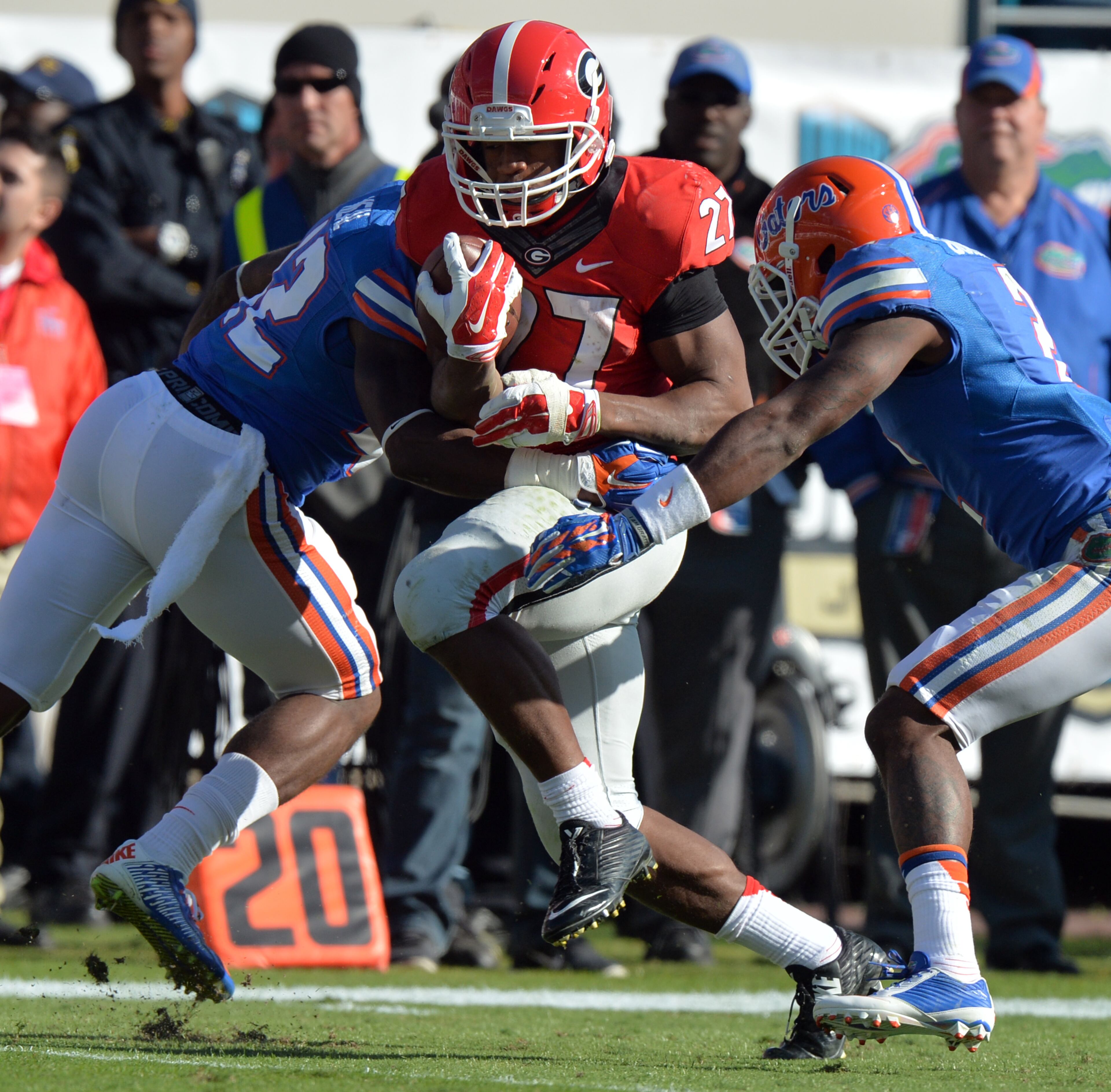 Georgia Bulldogs running back Nick Chubb was able to break the tackle of Florida defenders Keanu Neal, left, and Quincy Wilson in route to first quarter touchdown. The Bulldogs fell to 38-20 to Florida in Jacksonville Saturday November 1, 2014. BRANT SANDERLIN / BSANDERLIN@AJC.COM