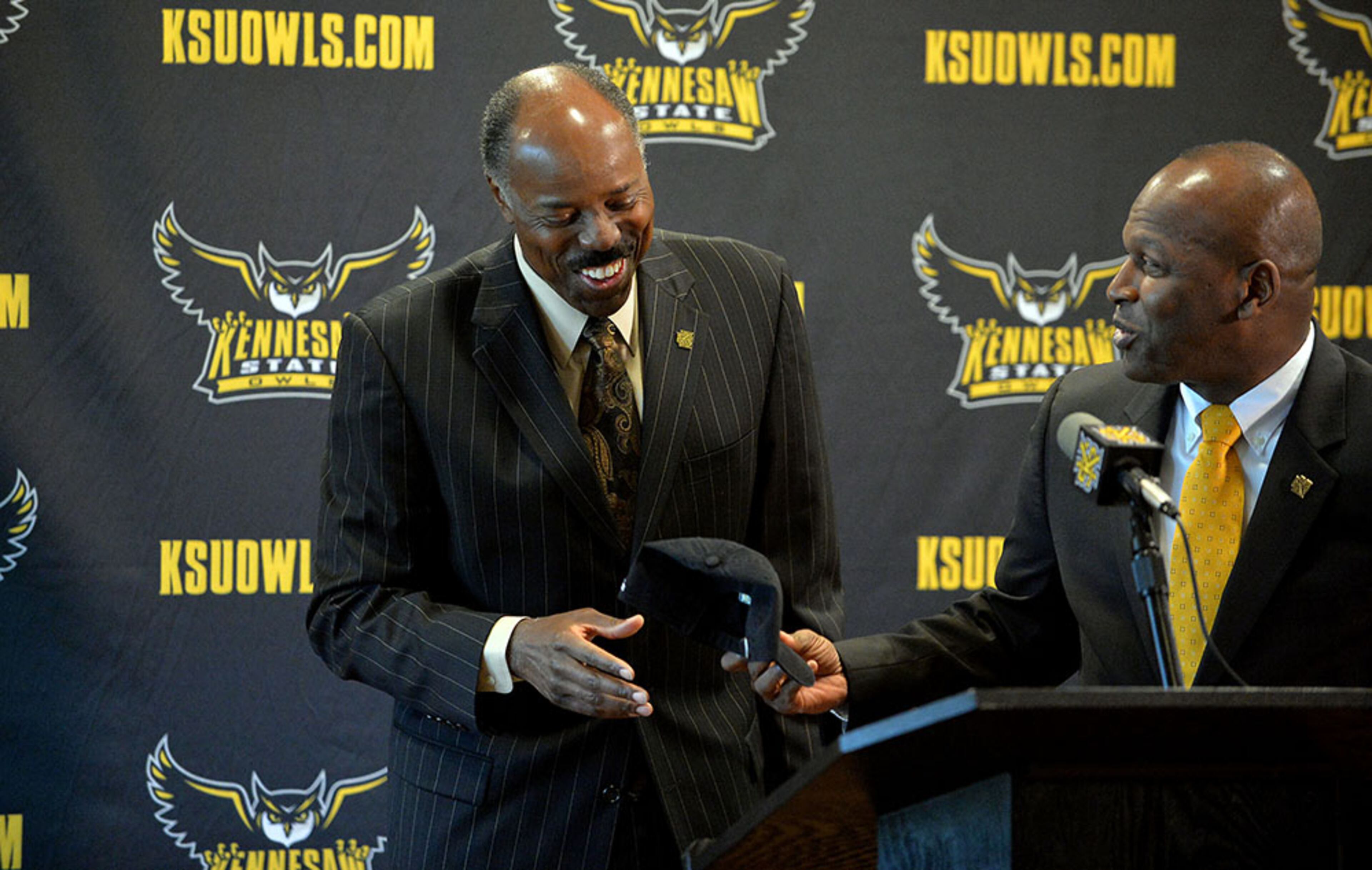 Kennesaw State University athletic director Vaughn Williams (right) gives coach Al Skinner as hat as he introduces him as the new men's head basketball coach during a press conference Tuesday, April 28, 2015. Skinner is a former Big East and ACC coach.