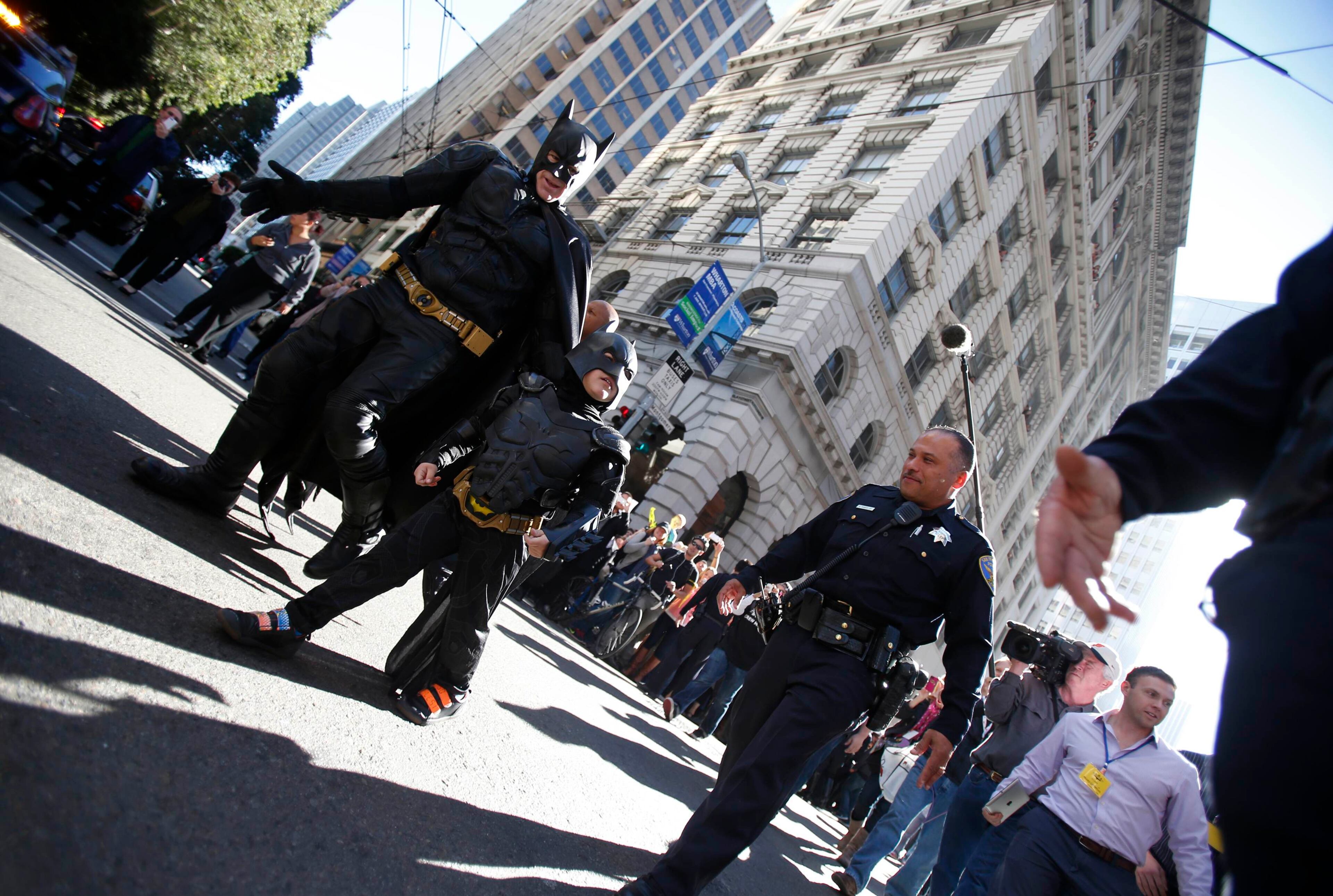 Five-year-old leukemia survivor Miles Scott dressed as "Batkid" and a man dressed as Batman are escorted by police officers back to their Batmobile after they apprehended "The Riddler" as part of a day arranged by the Make-A-Wish Foundation in San Francisco, California November 15, 2013. The young cancer survivor will be treated to various super hero scenarios including receiving a commendation at San Francisco City Hall.