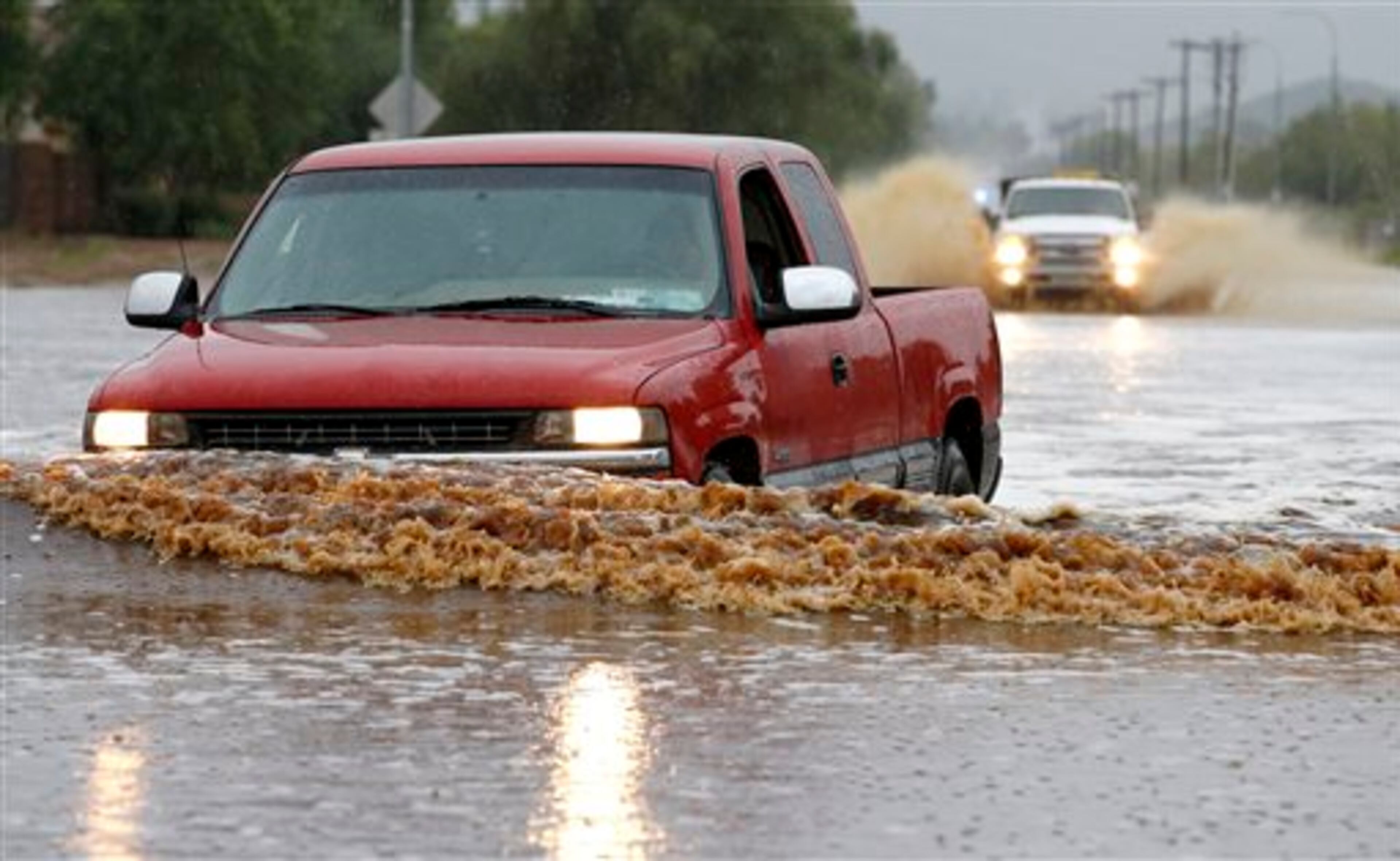 Drivers attempt to navigate their vehicles through severely flooded streets as heavy rains pour down Monday, Sept. 8, 2014, in Phoenix. Storms that flooded several Phoenix-area freeways and numerous local streets during the Monday morning commute set an all-time record for rainfall in Phoenix in a single day. (AP Photo/Ross D. Franklin)